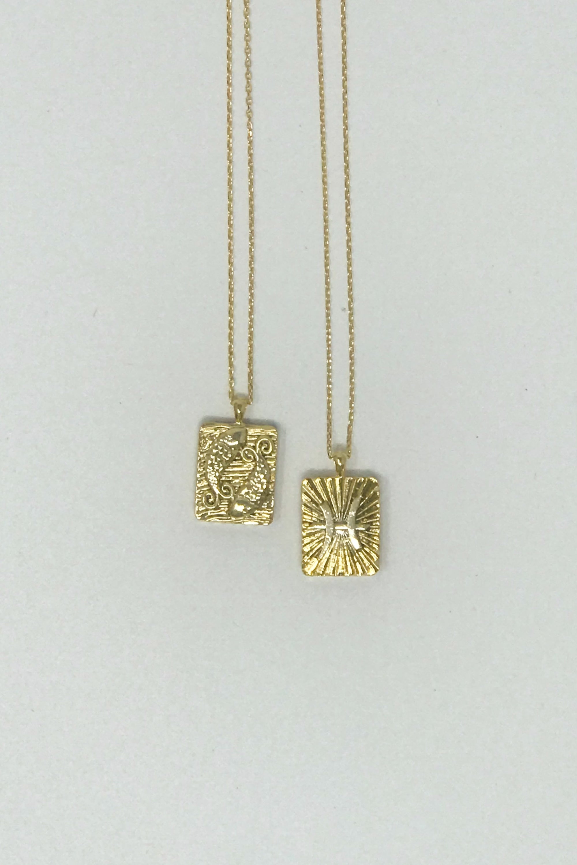 Elegant reversible gold pendant necklace featuring zodiac constellation signs, showcasing both sides of the design.