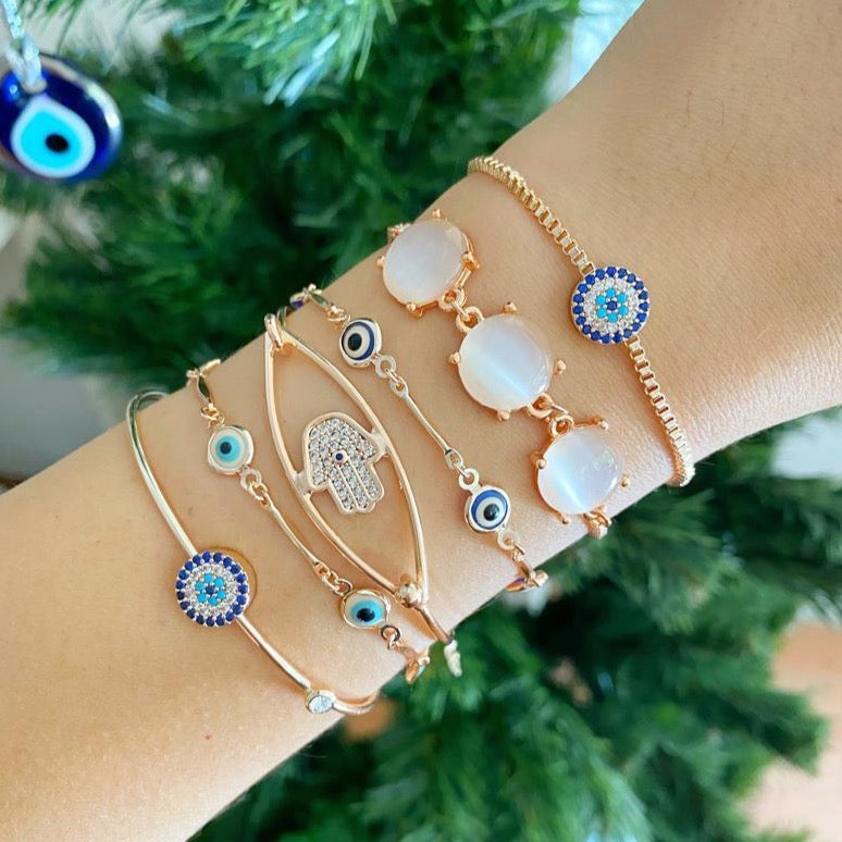 A beautiful rose gold bracelet set featuring an evil eye charm and hamsa hand design, showcasing intricate details and an adjustable fit.
