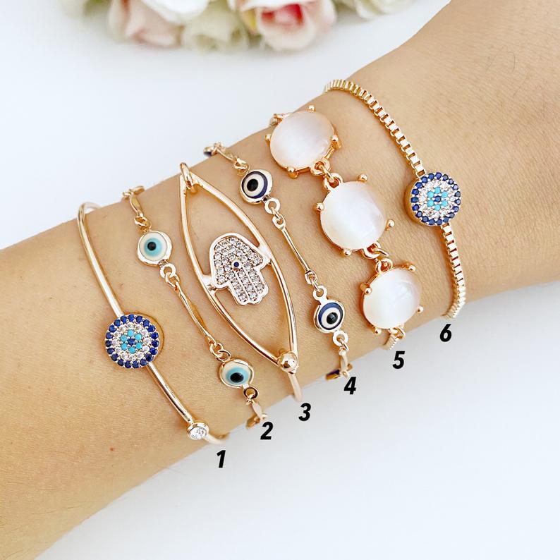 A beautiful rose gold bracelet set featuring an evil eye charm and hamsa hand design, showcasing intricate details and an adjustable fit.