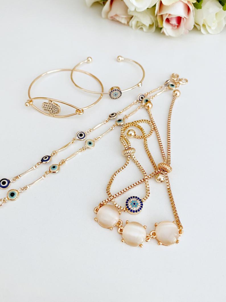 A beautiful rose gold bracelet set featuring an evil eye charm and hamsa hand design, showcasing intricate details and an adjustable fit.