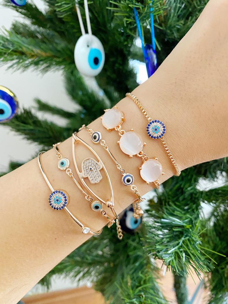 A beautiful rose gold bracelet set featuring an evil eye charm and hamsa hand design, showcasing intricate details and an adjustable fit.
