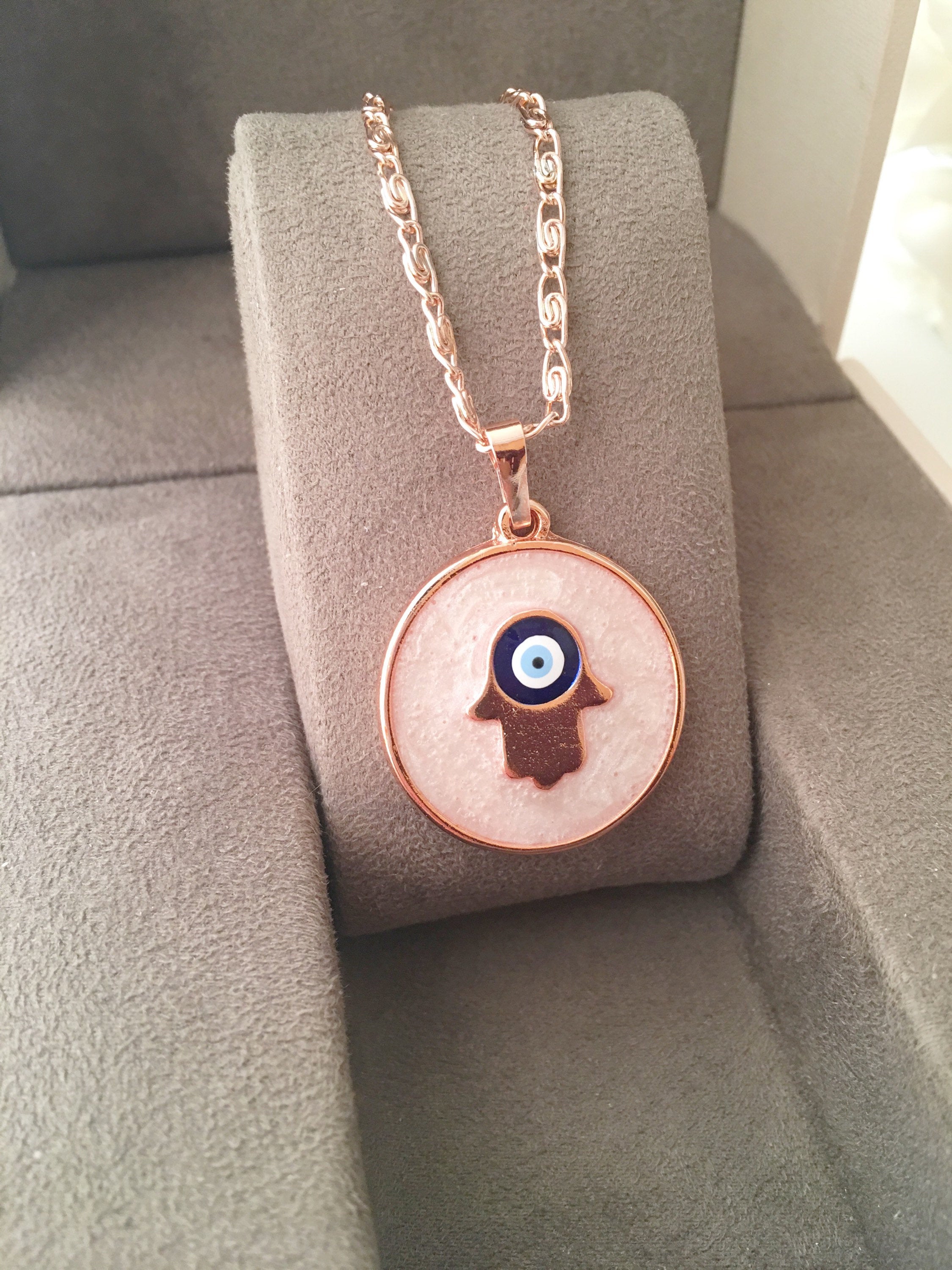 Rose Gold Evil Eye Necklace featuring Mother of Pearl, showcasing intricate design and charm options.