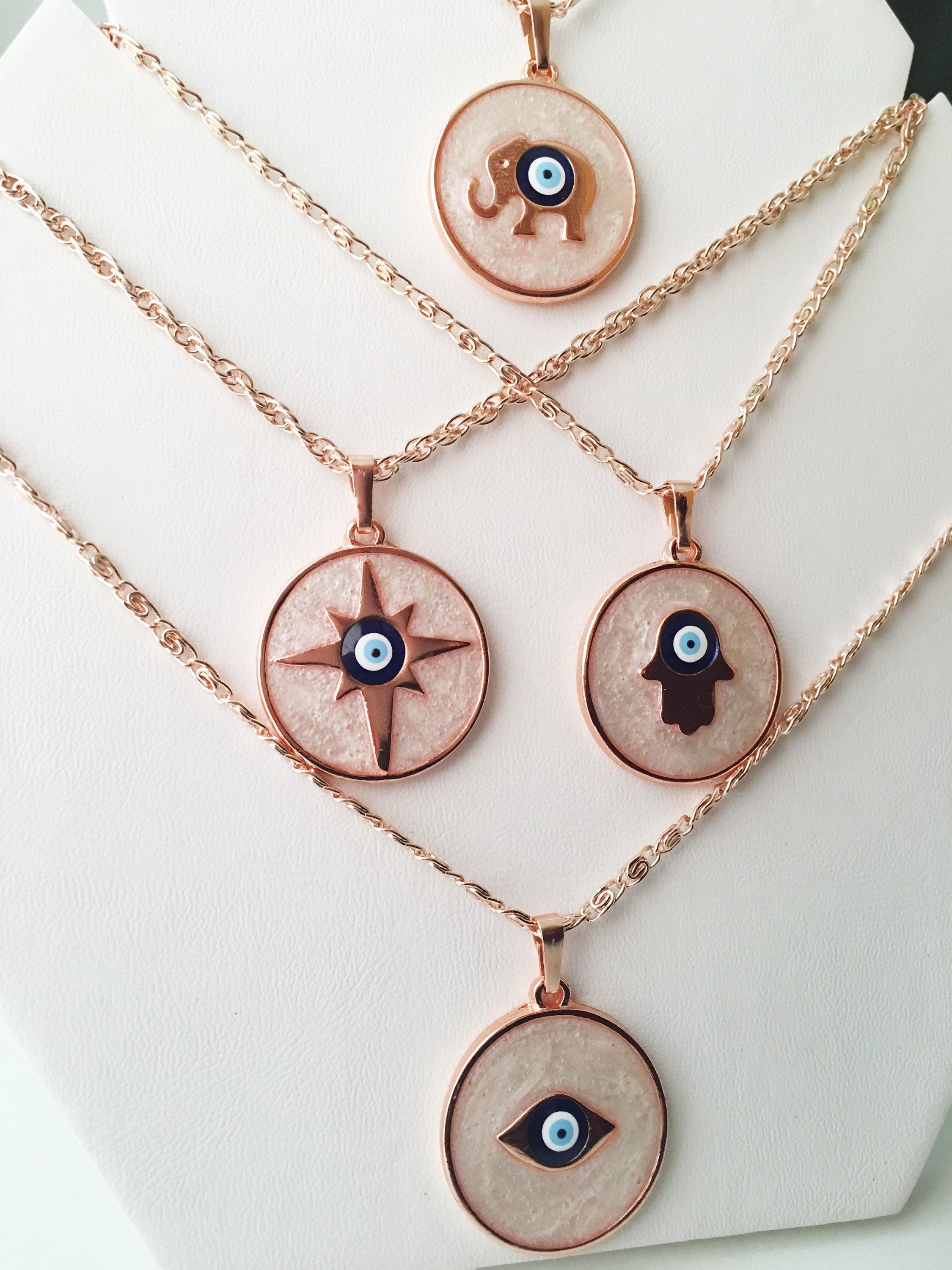 Rose Gold Evil Eye Necklace featuring Mother of Pearl, showcasing intricate design and charm options.