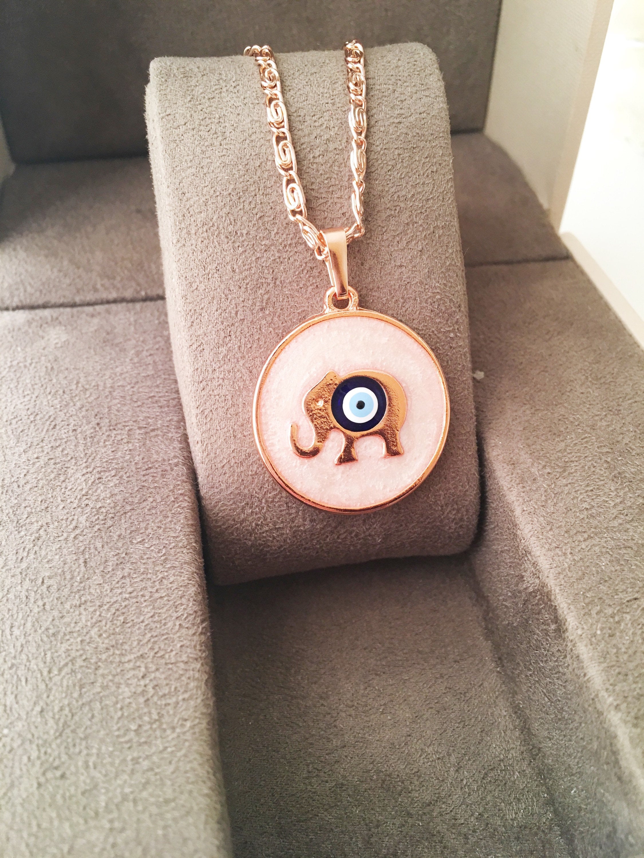 Rose Gold Evil Eye Necklace featuring Mother of Pearl, showcasing intricate design and charm options.