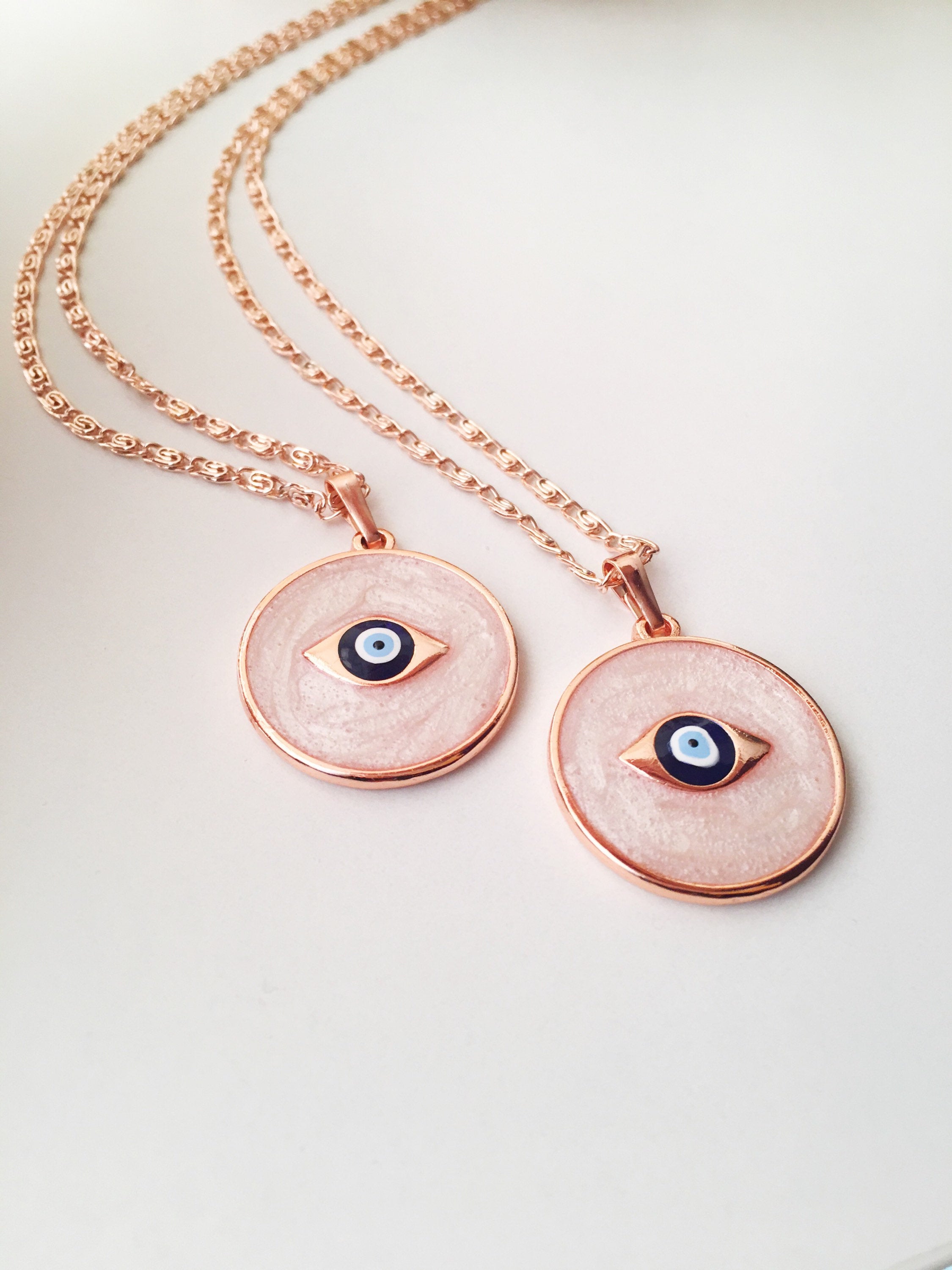 Rose Gold Evil Eye Necklace featuring Mother of Pearl, showcasing intricate design and charm options.