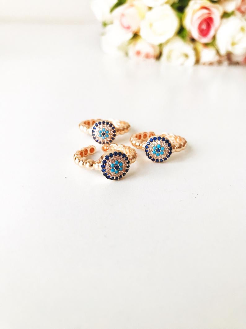 A beautiful rose gold evil eye ring featuring a blue evil eye and sparkling cubic zirconia accents, adjustable for a perfect fit.