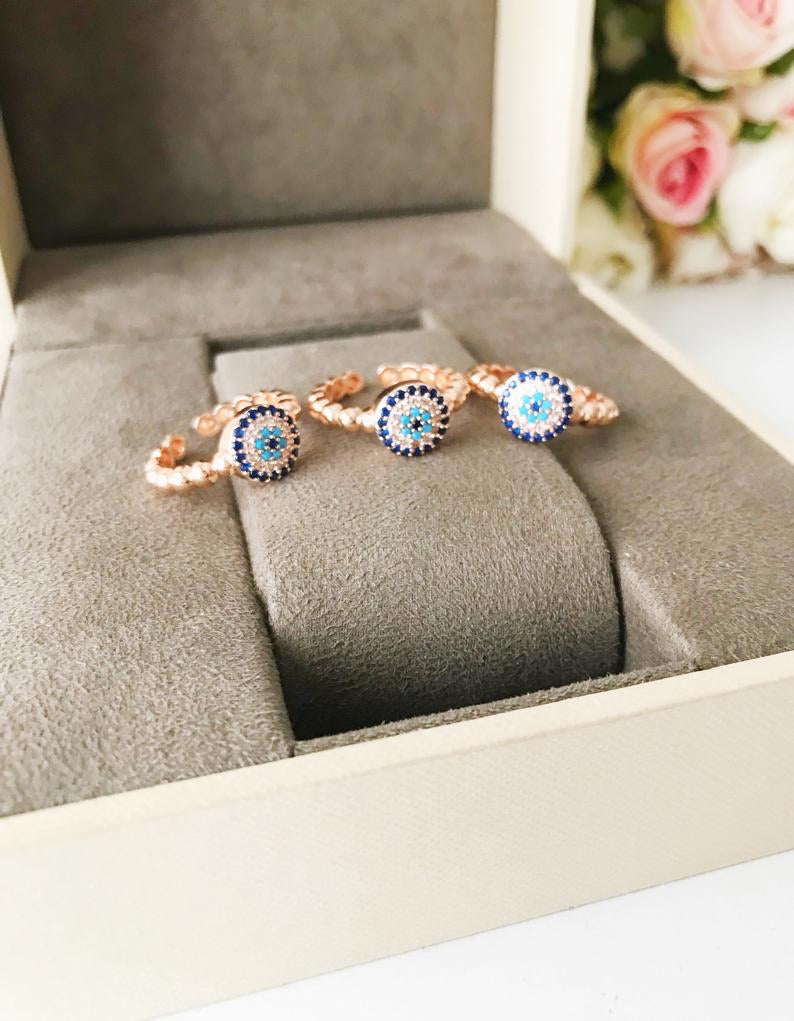 A beautiful rose gold evil eye ring featuring a blue evil eye and sparkling cubic zirconia accents, adjustable for a perfect fit.
