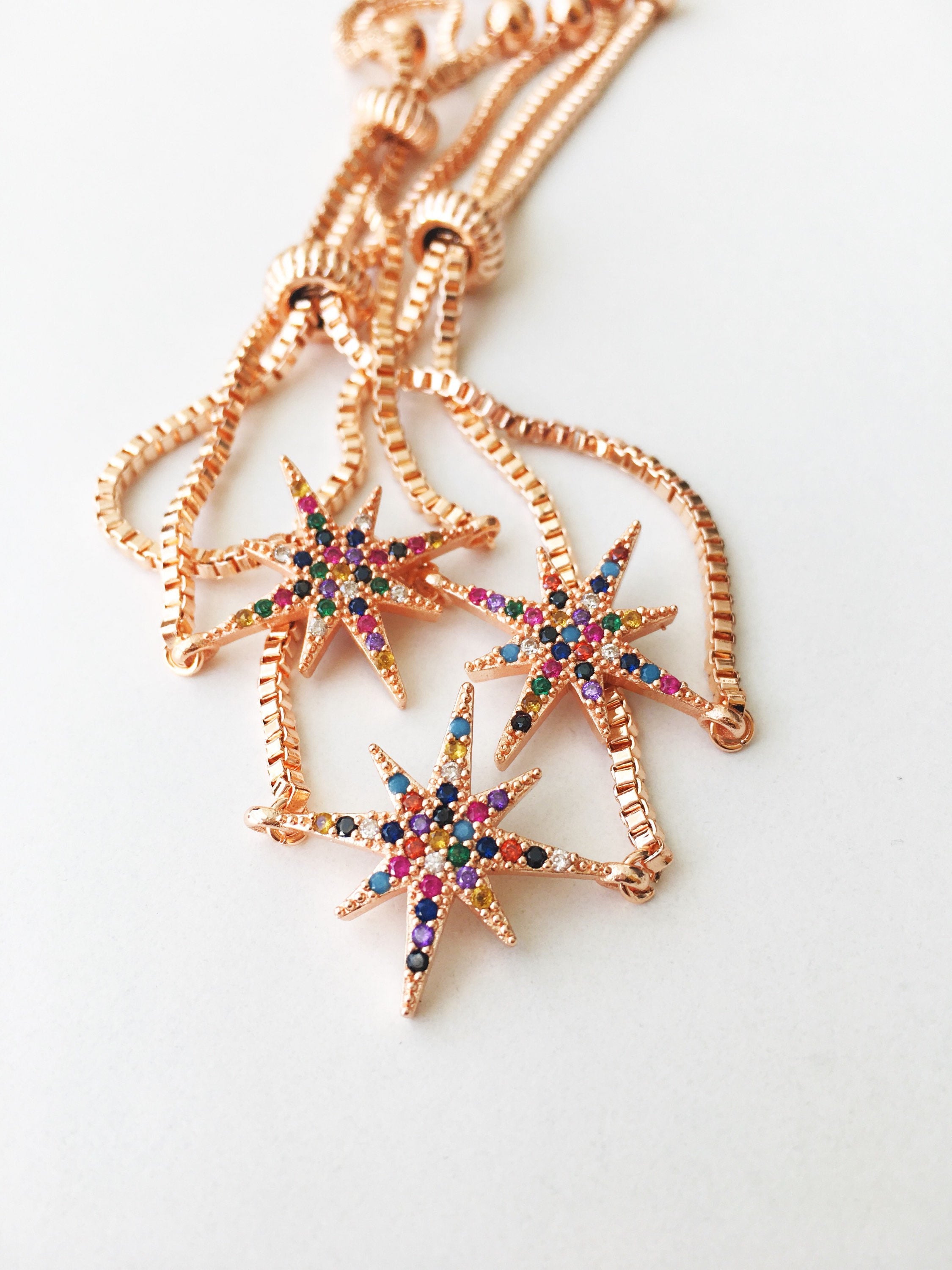 A beautiful rose gold star bracelet featuring colorful rainbow zirconia stones, adjustable stainless steel string, and a delicate star charm.