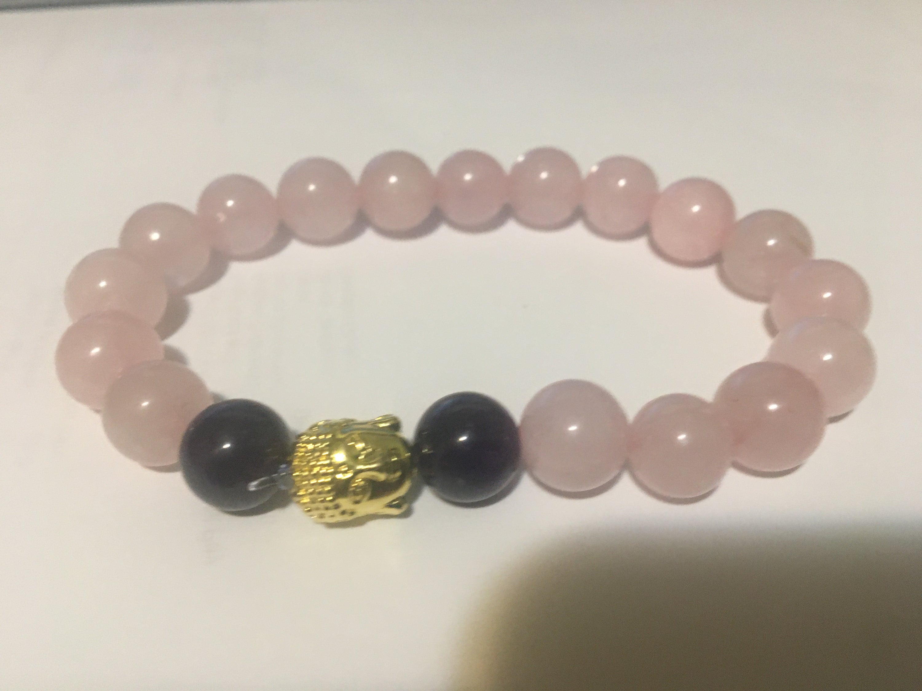 Rose Quartz and Black Obsidian bracelet featuring a Buddha head charm, showcasing natural gemstones in a stylish design.