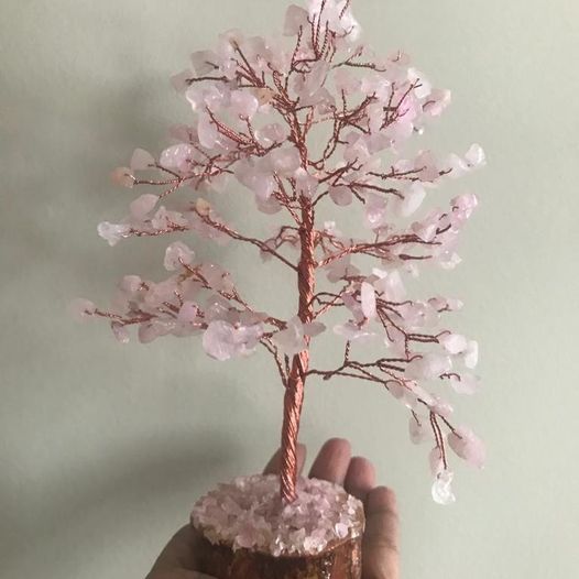 A beautiful Rose Quartz Gemstone Tree with 200 chips, featuring a wooden base and delicate pink crystals, symbolizing love and healing.
