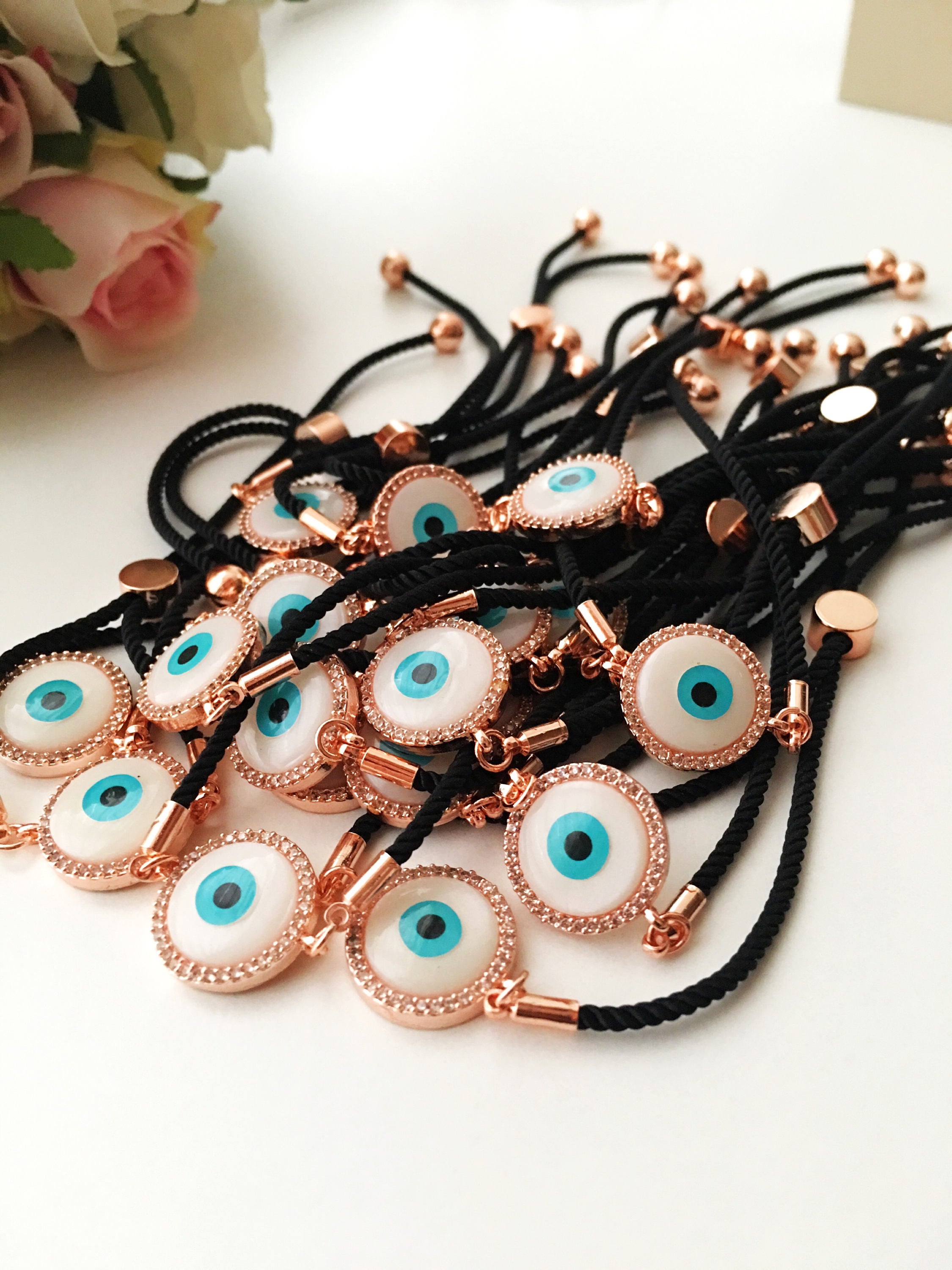 Round Evil Eye Bracelet featuring a black string and a mother of pearl charm, adorned with zirconia stones for added sparkle.