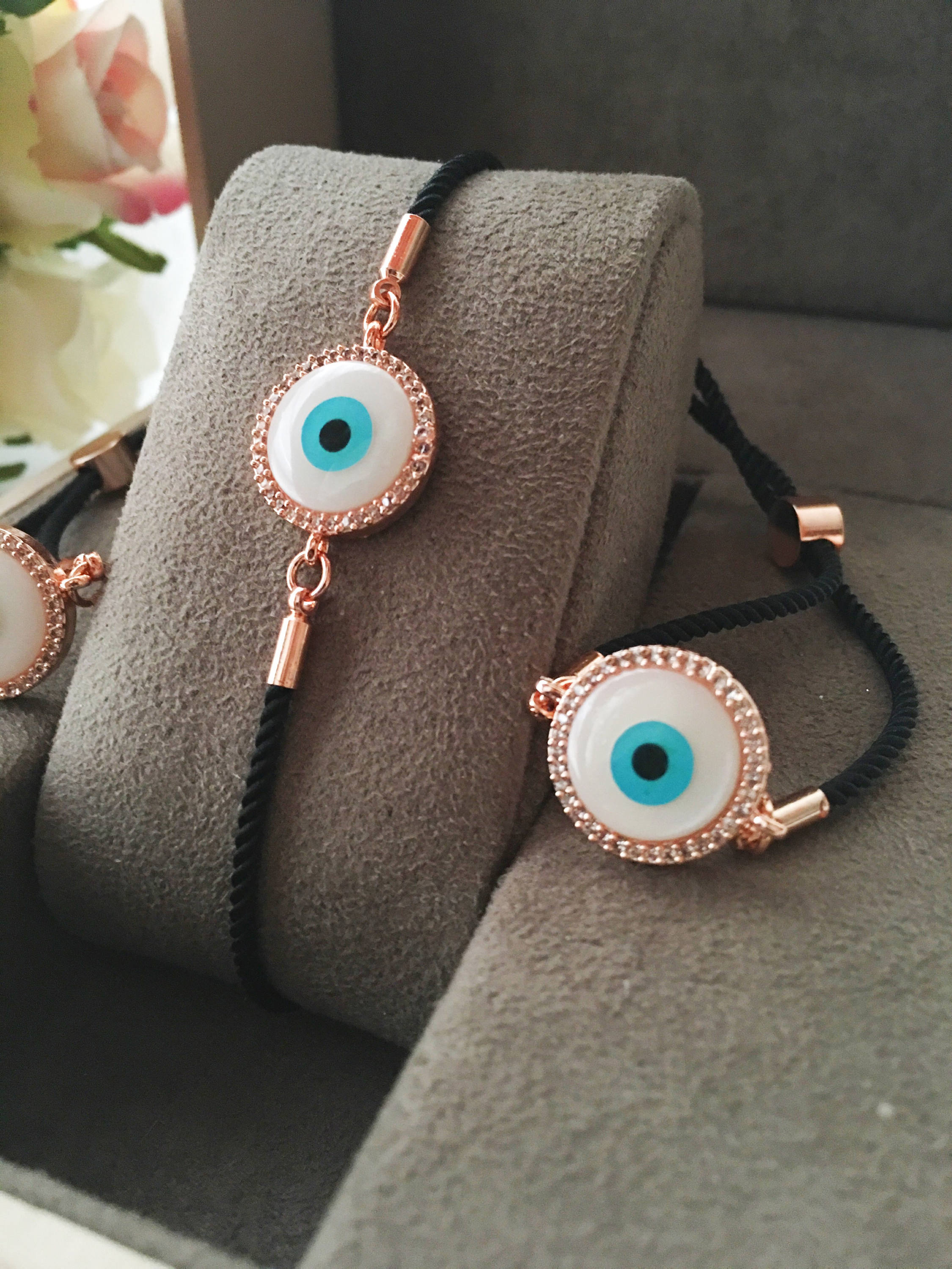 Round Evil Eye Bracelet featuring a black string and a mother of pearl charm, adorned with zirconia stones for added sparkle.