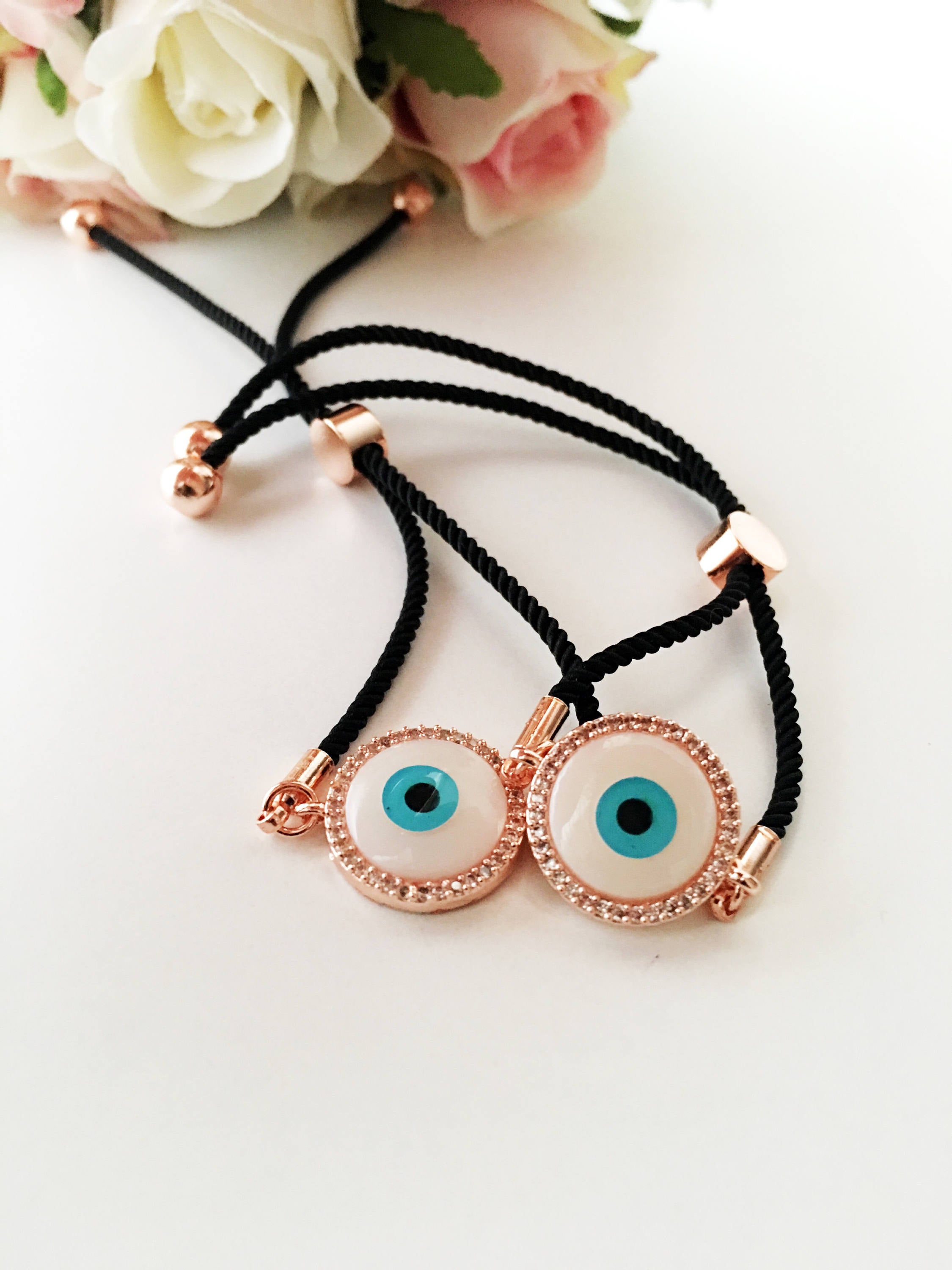 Round Evil Eye Bracelet featuring a black string and a mother of pearl charm, adorned with zirconia stones for added sparkle.