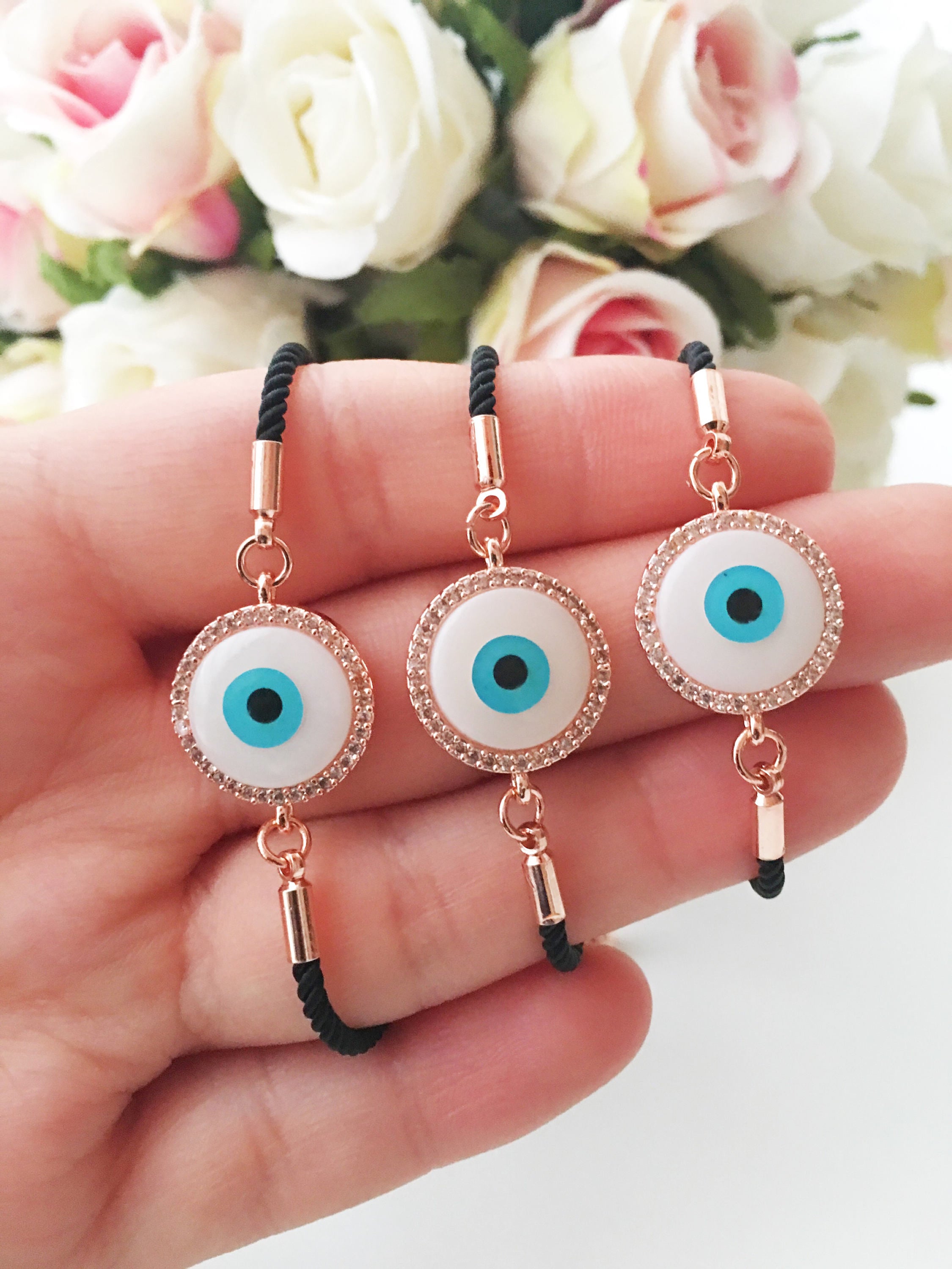 Round Evil Eye Bracelet featuring a black string and a mother of pearl charm, adorned with zirconia stones for added sparkle.
