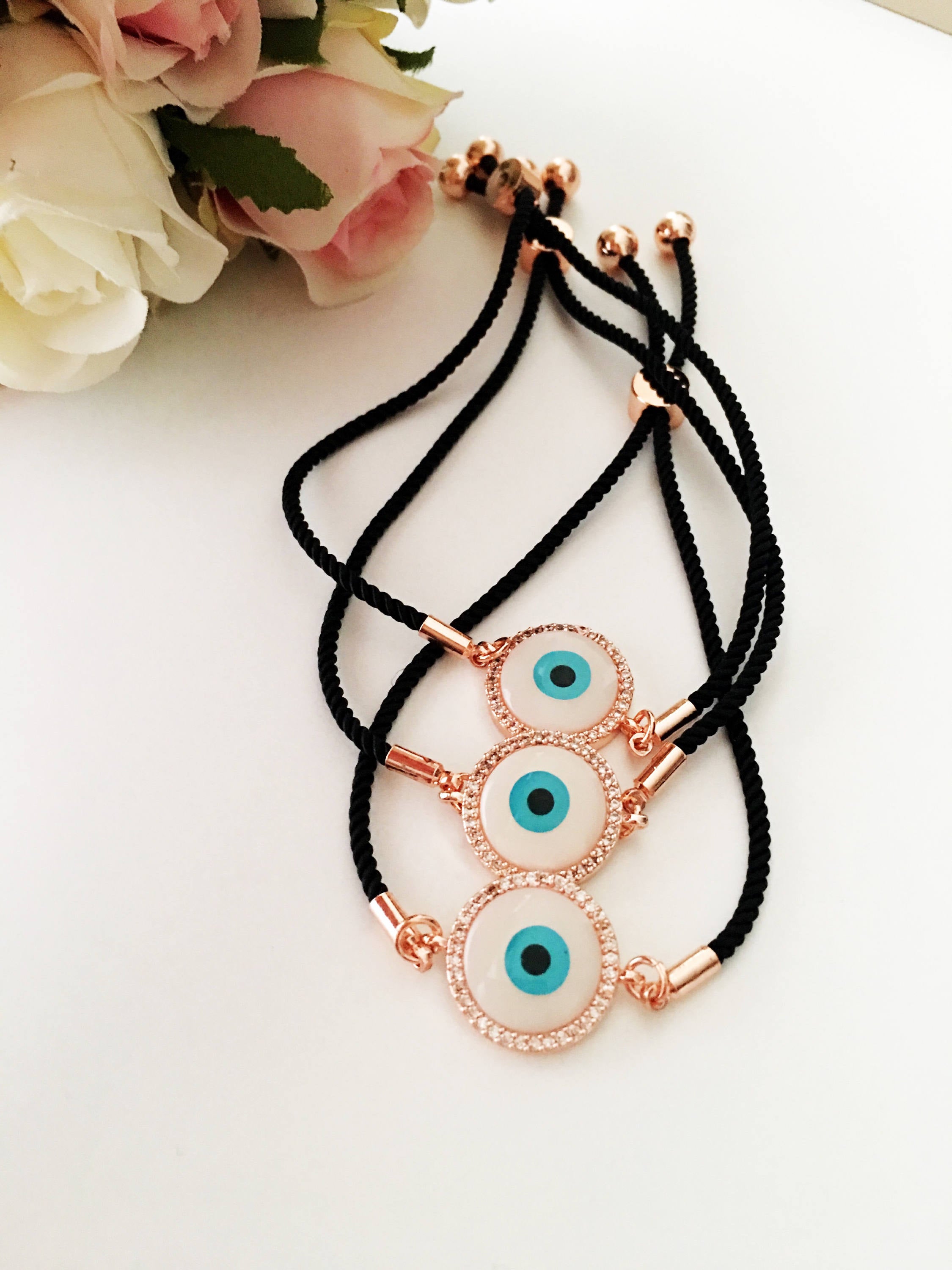 Round Evil Eye Bracelet featuring a black string and a mother of pearl charm, adorned with zirconia stones for added sparkle.