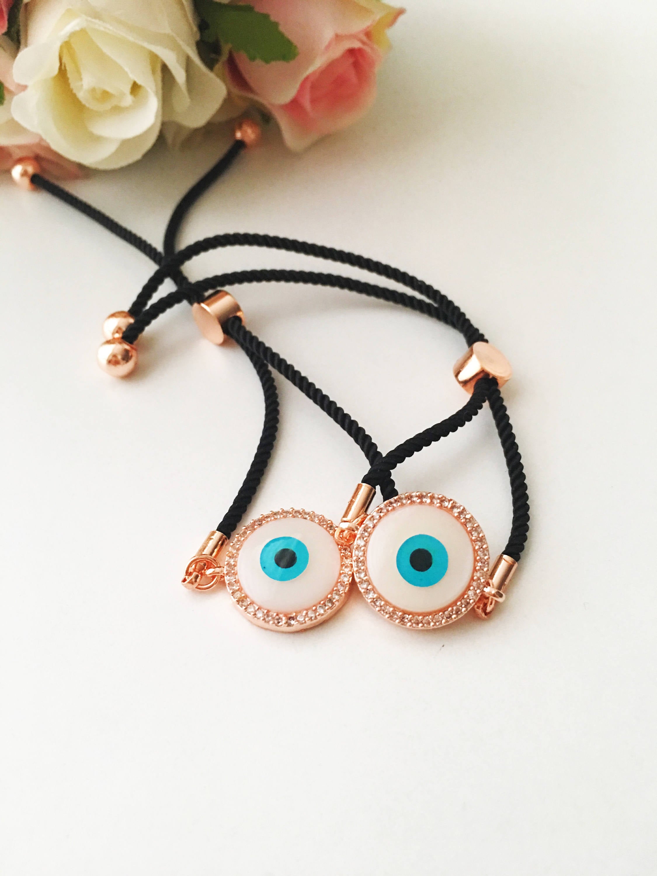 Round Evil Eye Bracelet featuring a black string and a mother of pearl charm, adorned with zirconia stones for added sparkle.