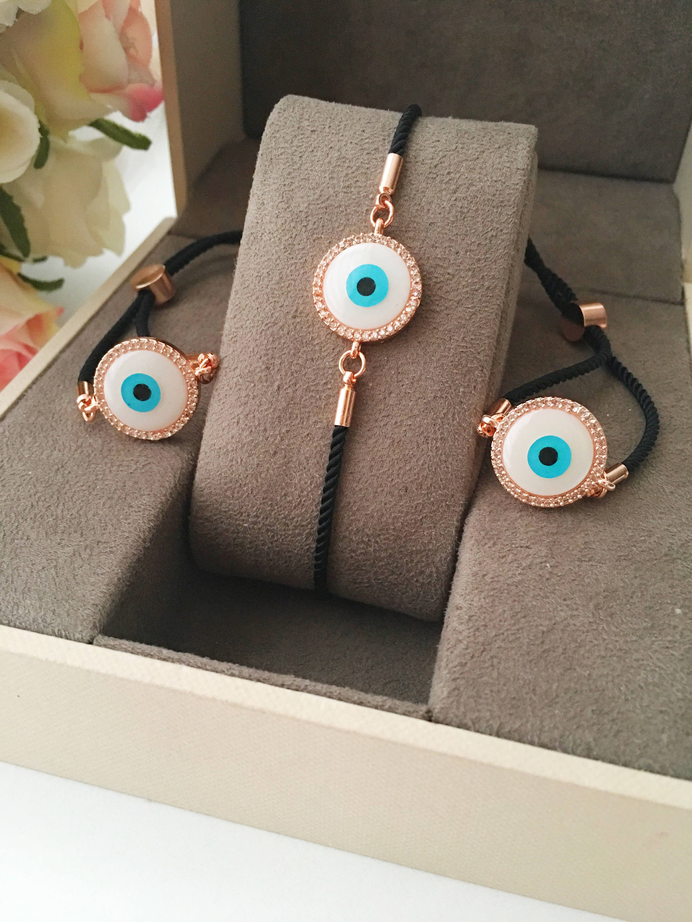Round Evil Eye Bracelet featuring a black string and a mother of pearl charm, adorned with zirconia stones for added sparkle.