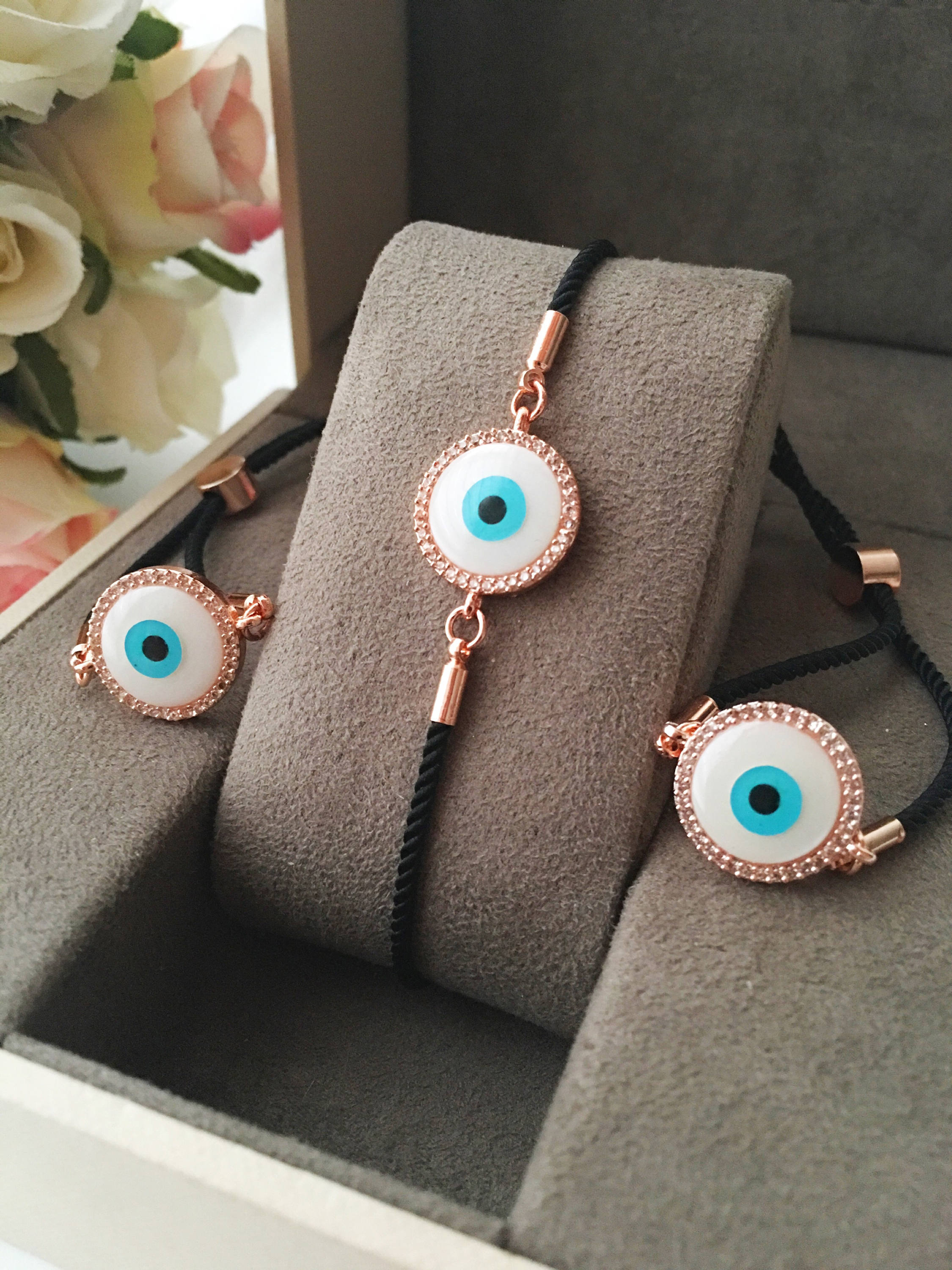Round Evil Eye Bracelet featuring a black string and a mother of pearl charm, adorned with zirconia stones for added sparkle.