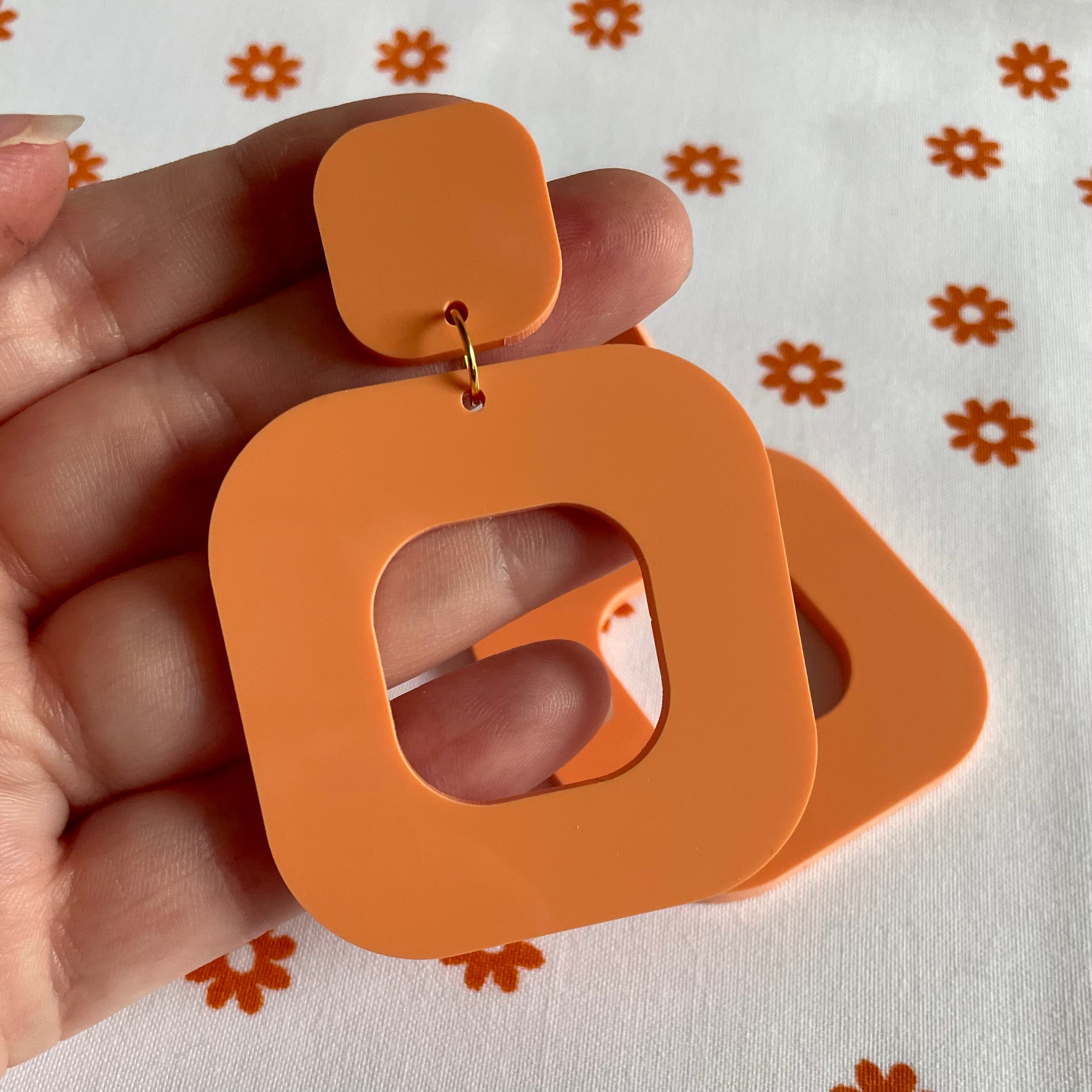 A pair of stylish rounded square earrings made from laser cut acrylic, showcasing vibrant colors and a modern design.