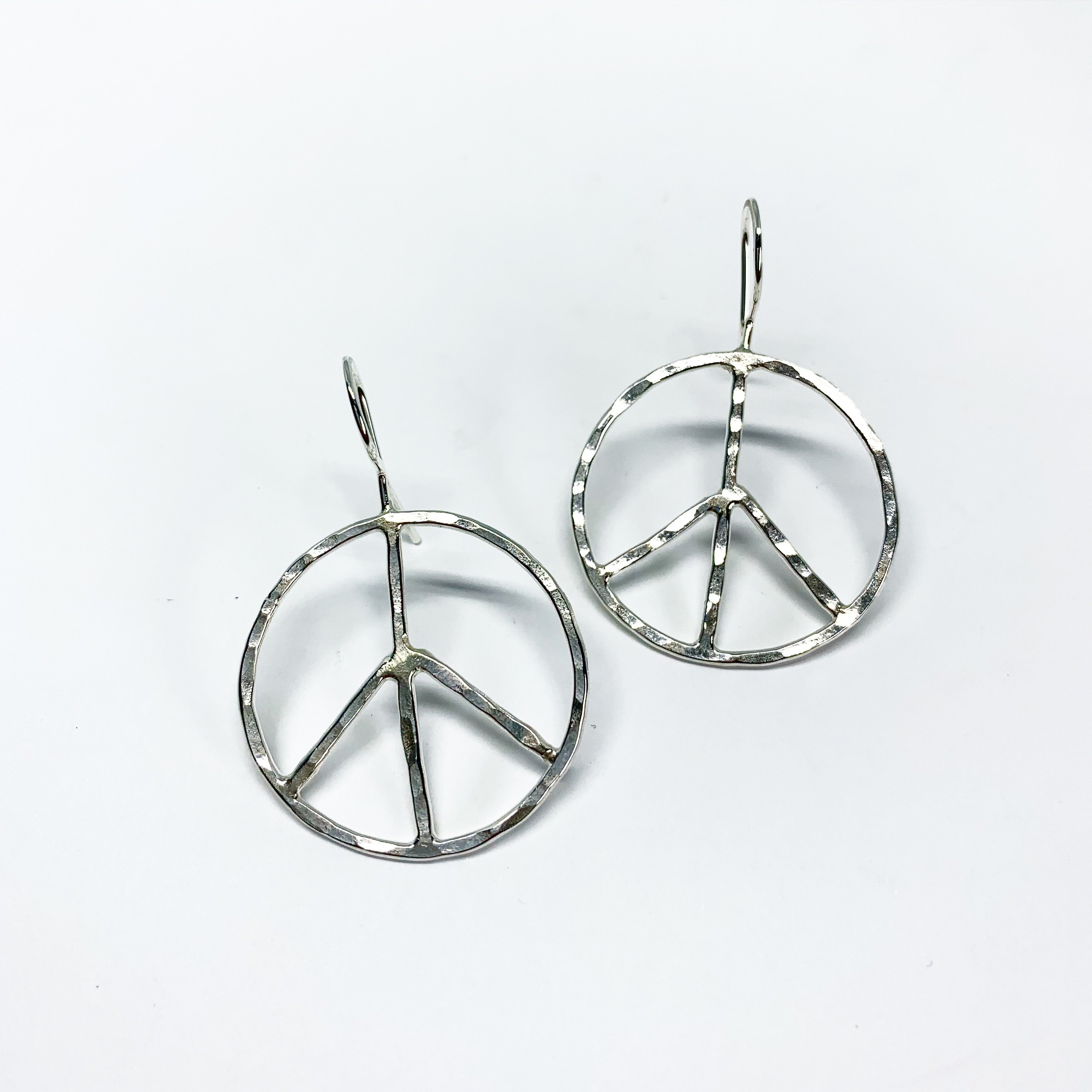Handcrafted rustic peace sign earrings made from recycled metals, featuring a hammered texture and measuring 1 inch in diameter.