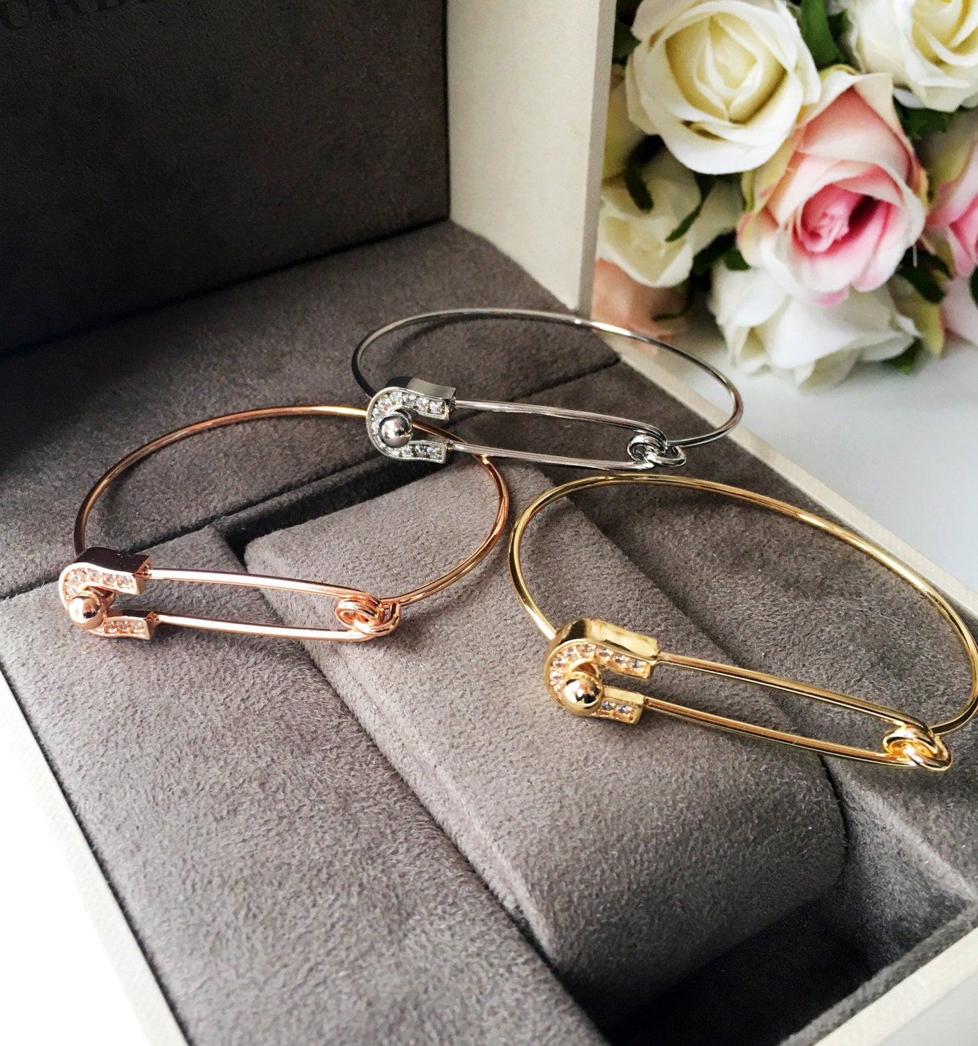Stylish Safety Pin Bangle Bracelet in silver, gold, and rose gold with zirconia accents, showcasing a modern design.
