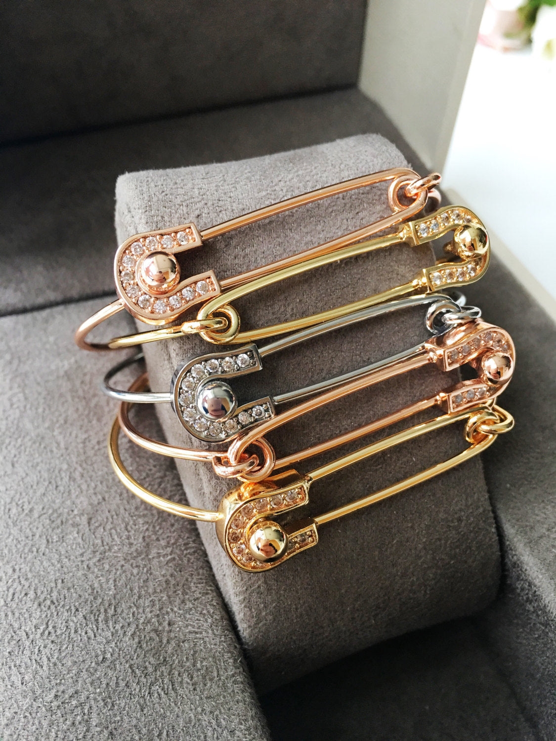 Stylish Safety Pin Bangle Bracelet in silver, gold, and rose gold with zirconia accents, showcasing a modern design.