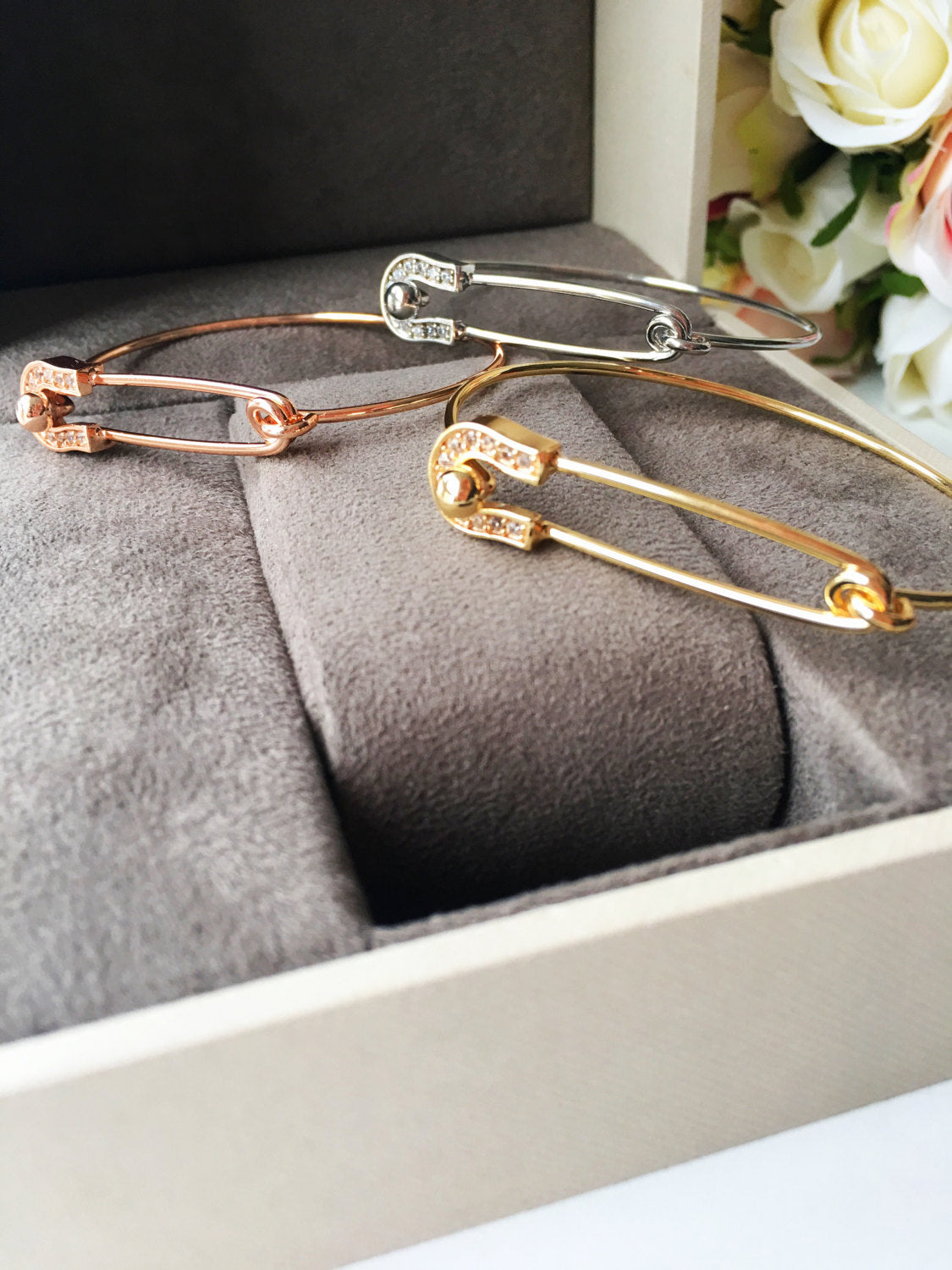 Stylish Safety Pin Bangle Bracelet in silver, gold, and rose gold with zirconia accents, showcasing a modern design.