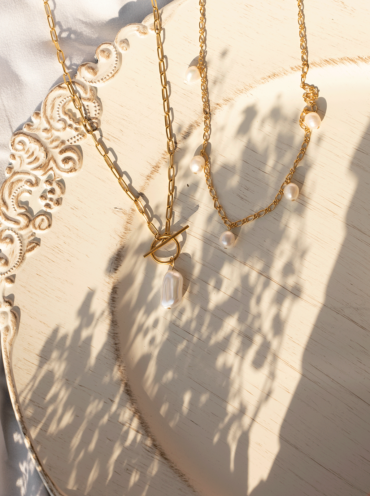 SAKURA Necklace featuring white freshwater pearls on an 18k gold plated Figaro link chain, showcasing elegance and style.
