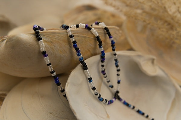 Handcrafted seed bead bracelet with 'Let it Go' in Morse code, featuring blue, black, and white beads.