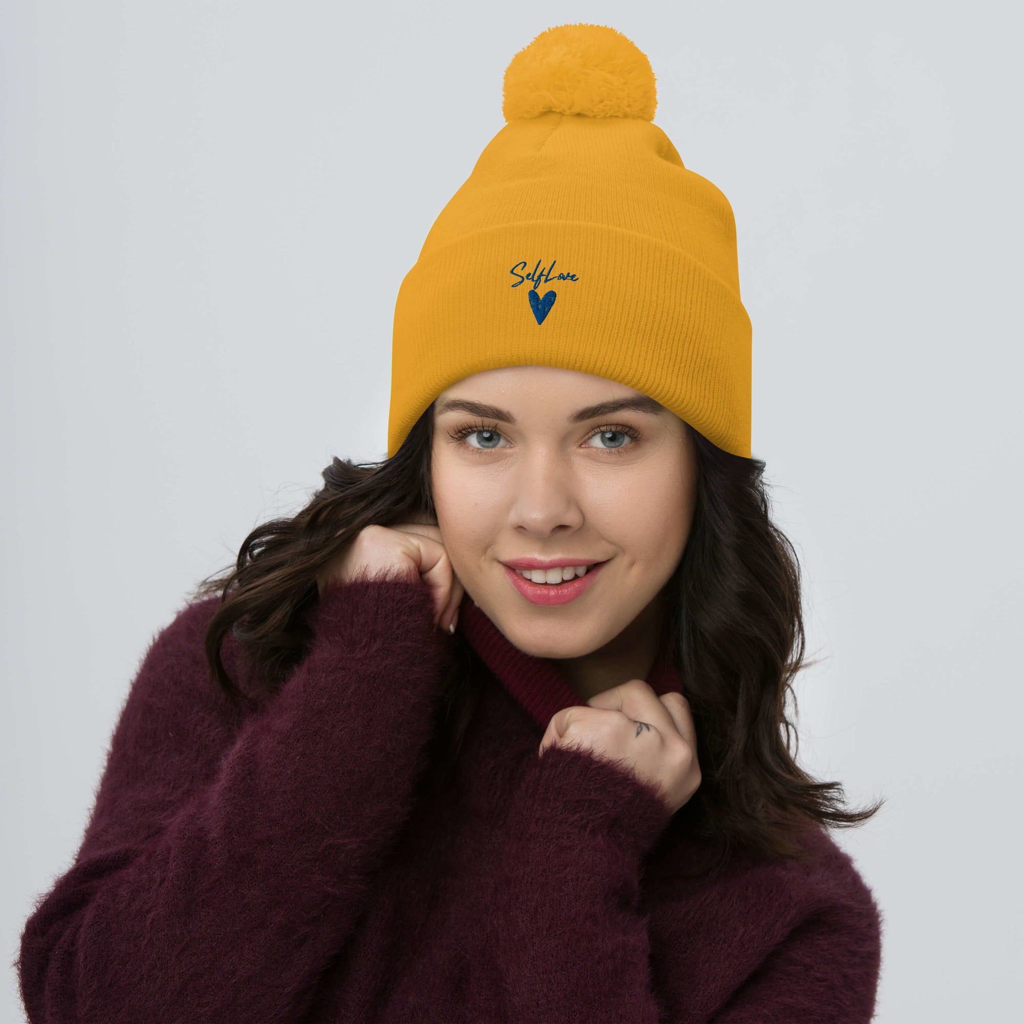Self Love Pom-Pom Beanie featuring embroidered design and playful pom-pom, perfect for winter wear.