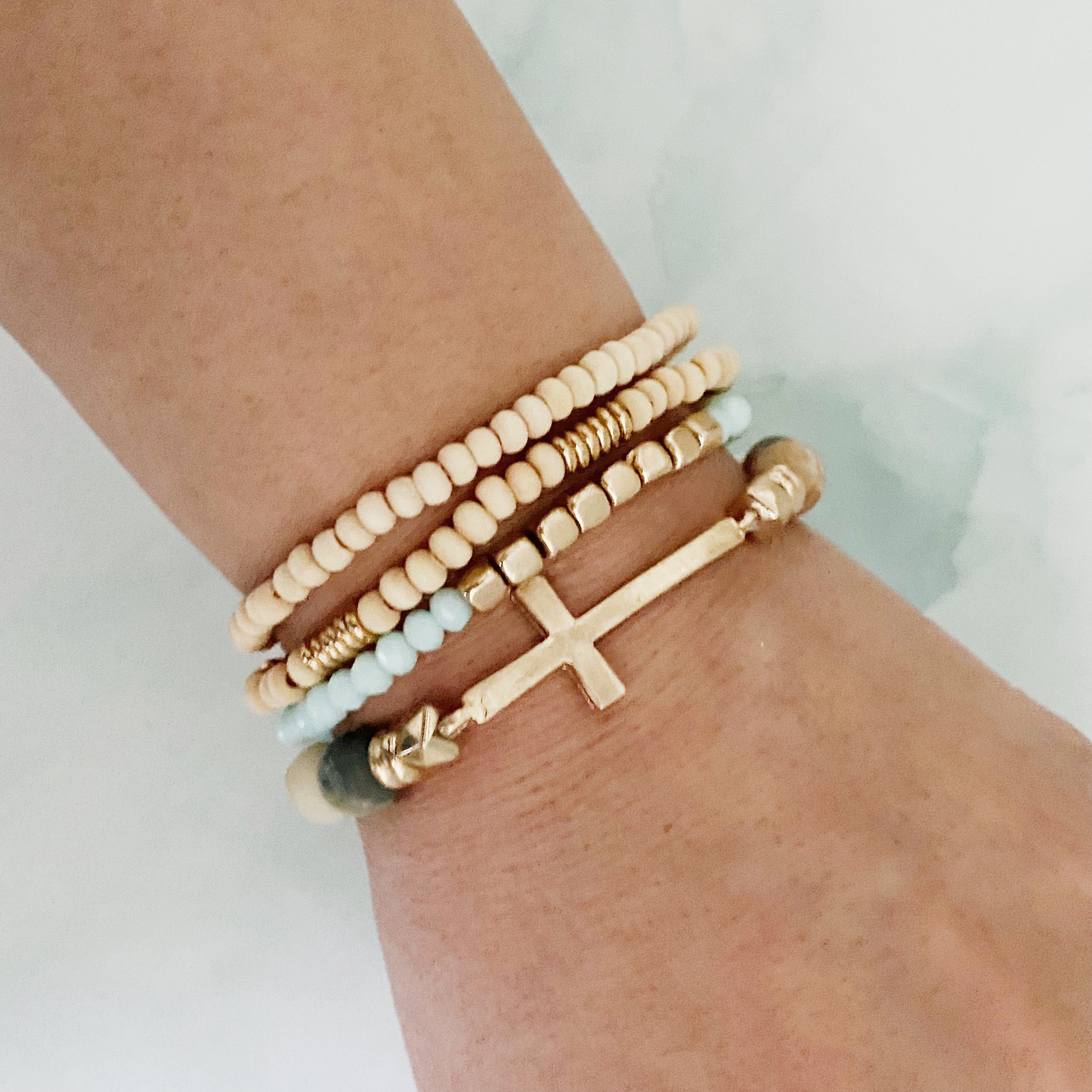 Set of 4 stylish bracelets featuring natural stone and wooden beads with a chic sided cross design.