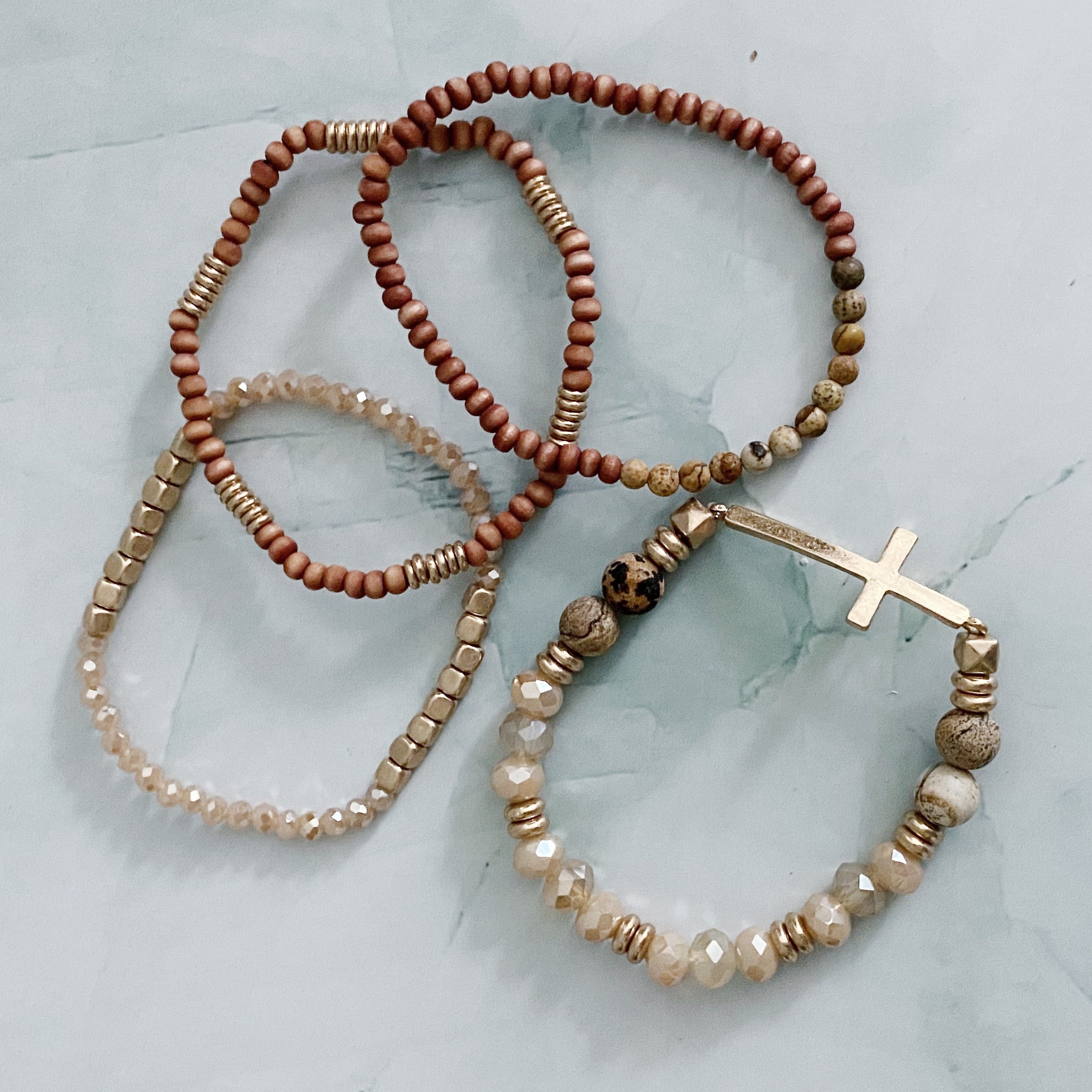 Set of 4 stylish bracelets featuring natural stone and wooden beads with a chic sided cross design.