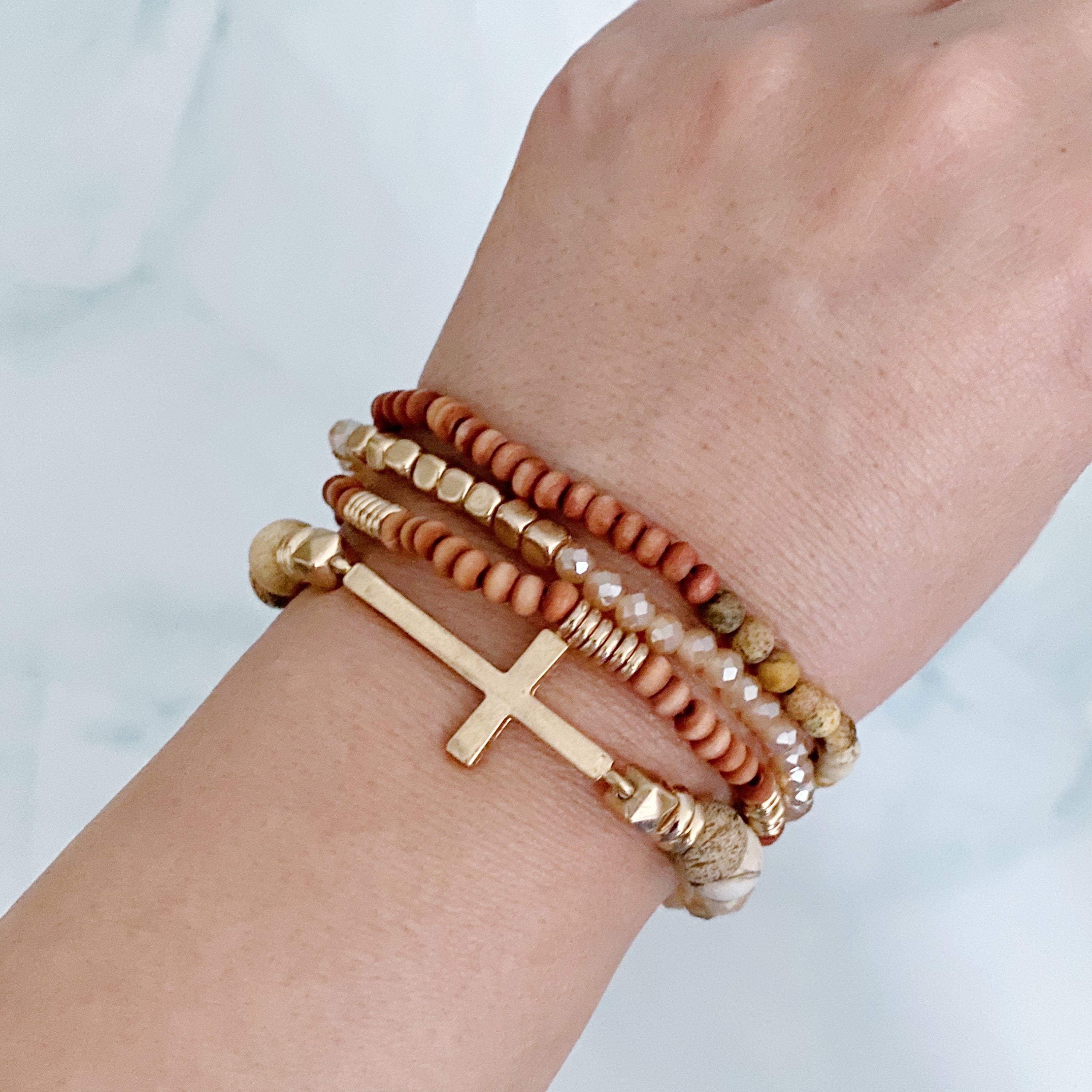 Set of 4 stylish bracelets featuring natural stone and wooden beads with a chic sided cross design.