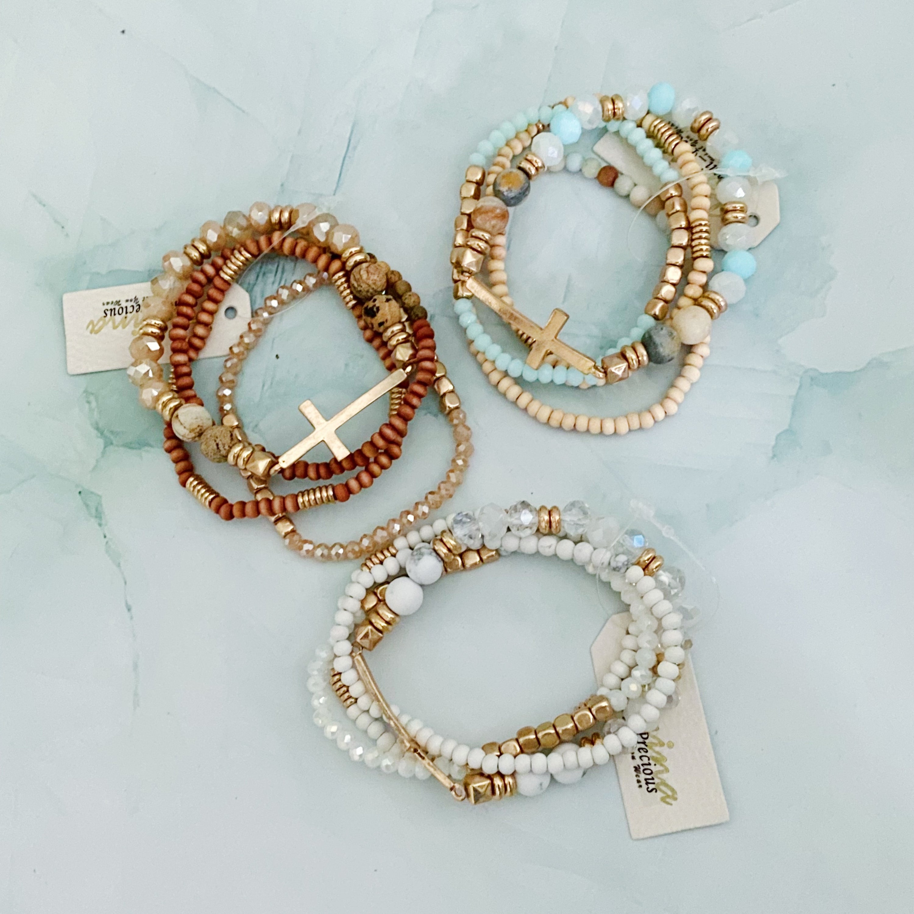 Set of 4 stylish bracelets featuring natural stone and wooden beads with a chic sided cross design.