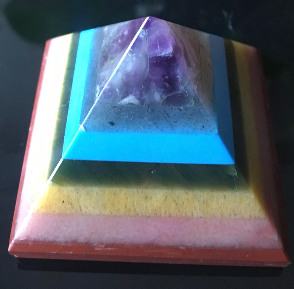 A colorful Seven Chakra Gemstone Pyramid made from natural gemstones, showcasing vibrant colors and intricate details.