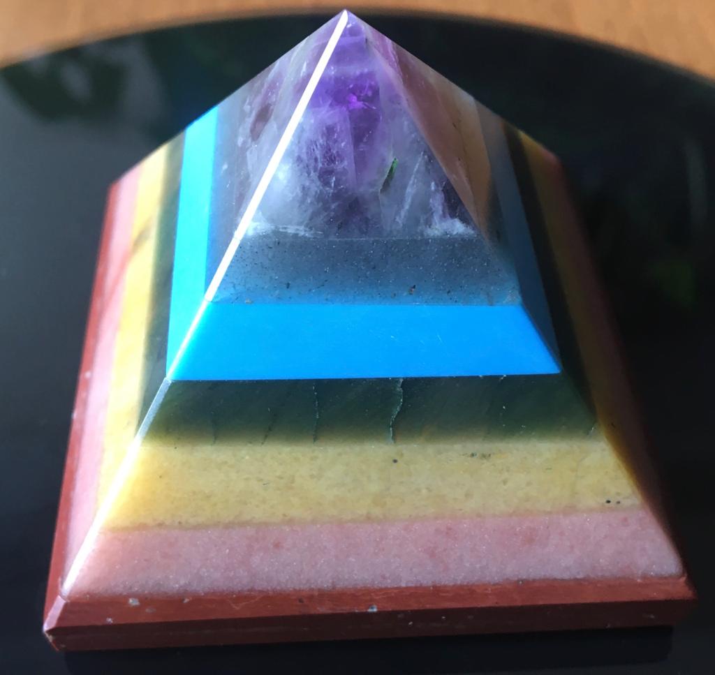 A colorful Seven Chakra Gemstone Pyramid made from natural gemstones, showcasing vibrant colors and intricate details.