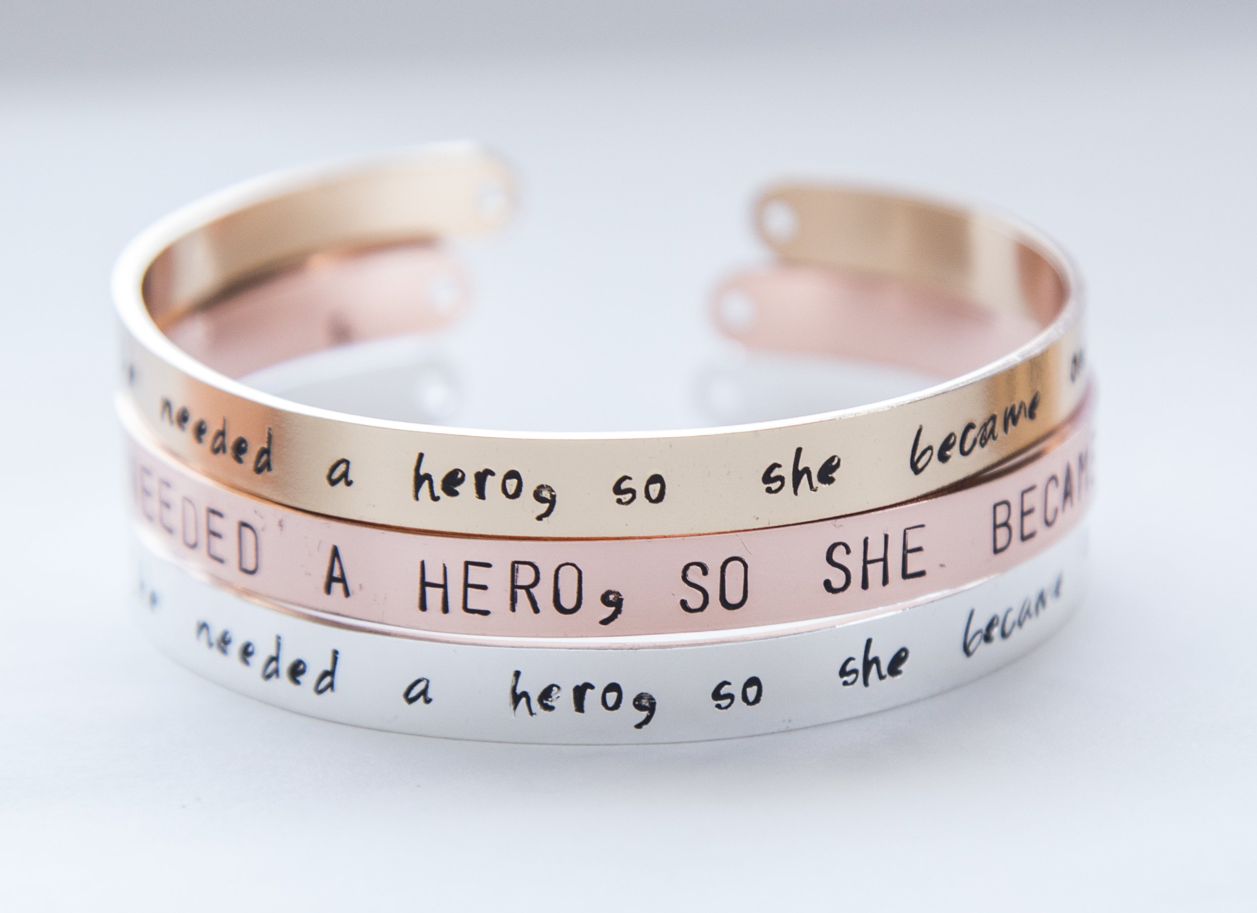 Hand-stamped cuff bracelet in silver, gold, and rose gold plating, showcasing unique lettering and adjustable design.