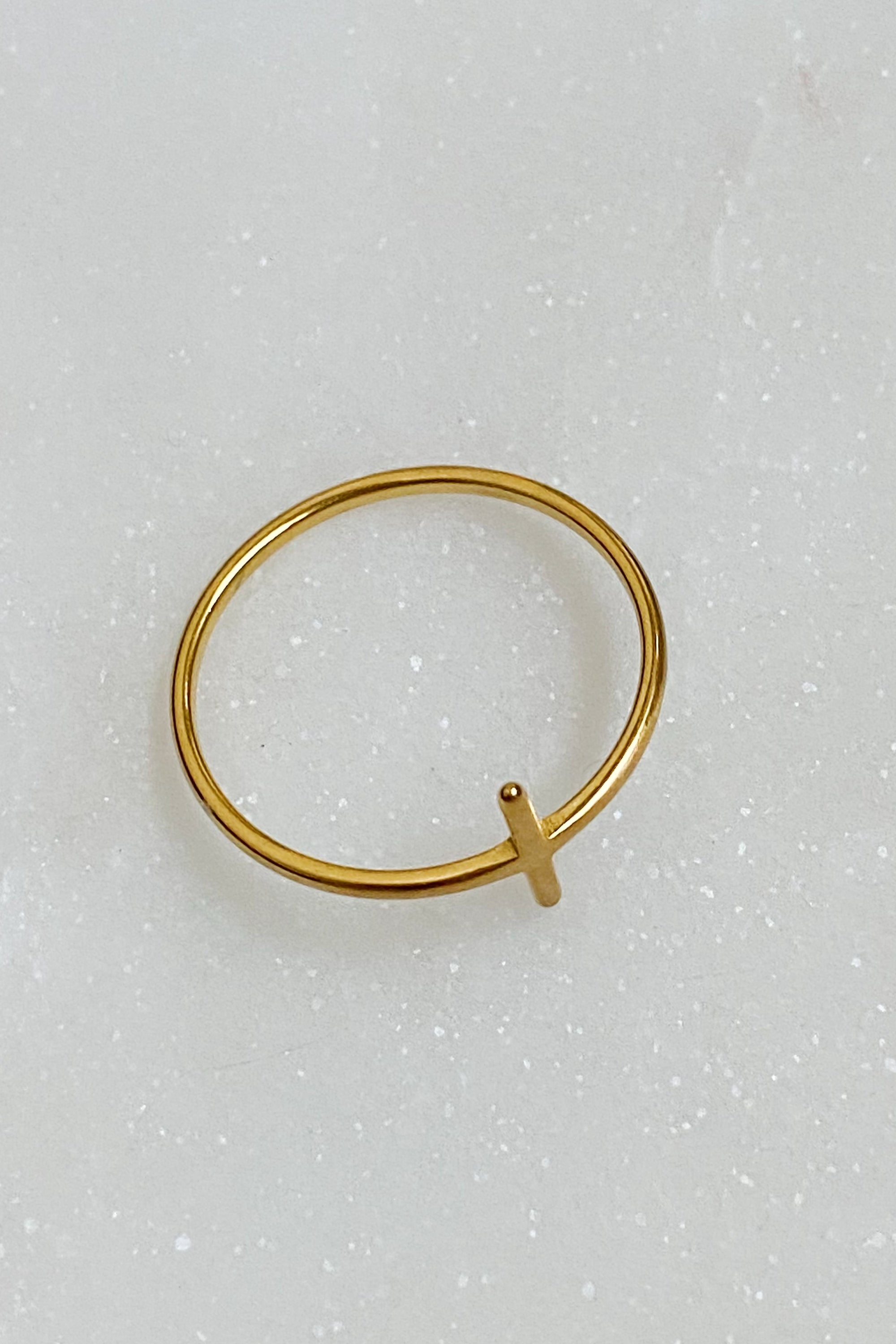 A slim dainty side cross ring made of stainless steel with 18K gold plating, showcasing its elegant design.