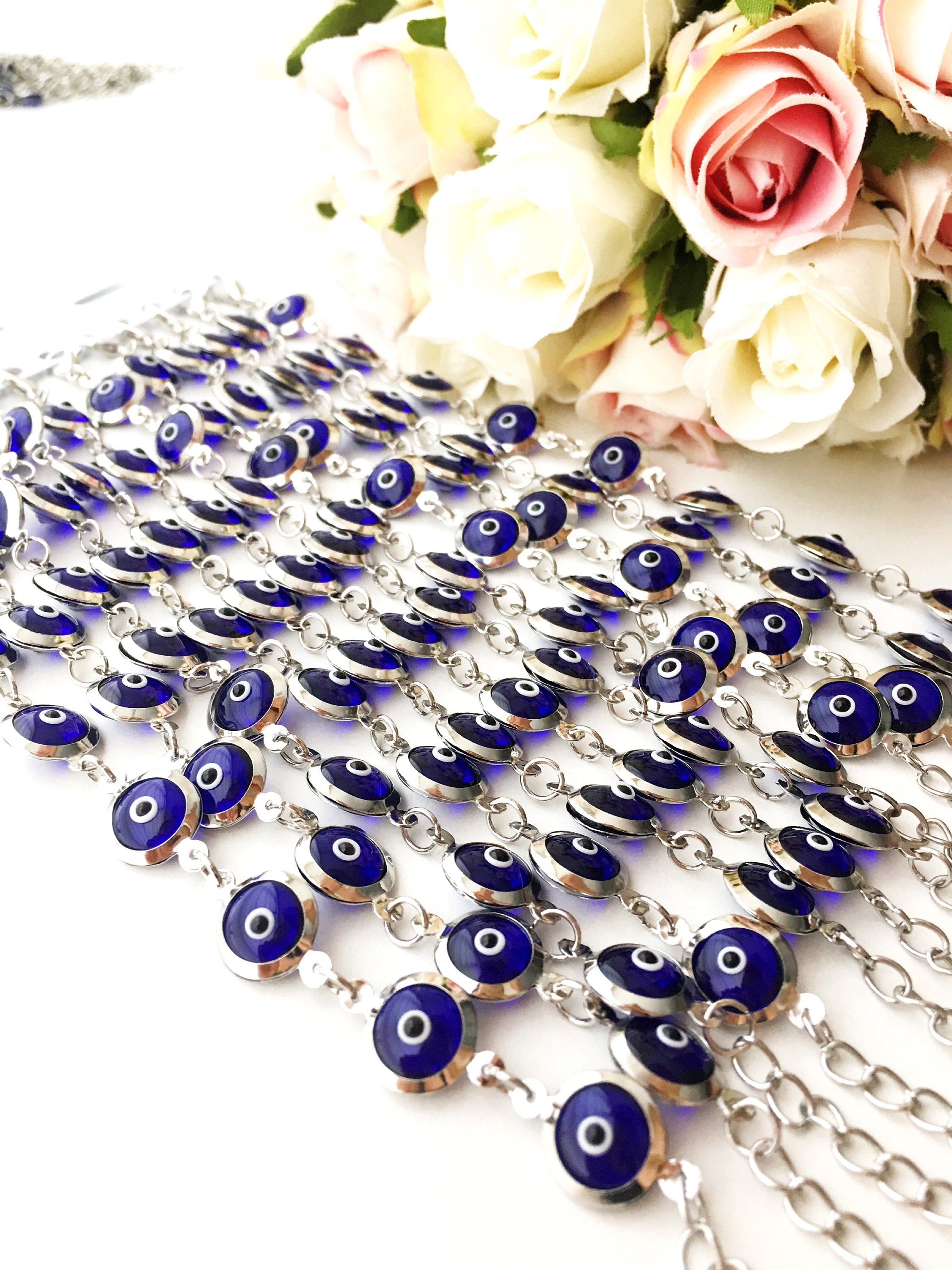 A beautiful silver chain bracelet featuring blue glass evil eye charms, showcasing handmade craftsmanship and elegant design.