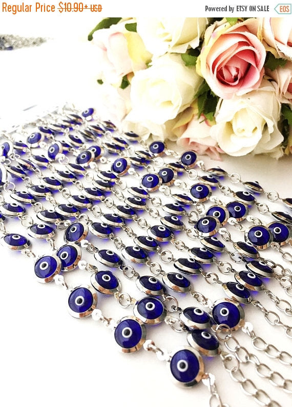 A beautiful silver chain bracelet featuring blue glass evil eye charms, showcasing handmade craftsmanship and elegant design.