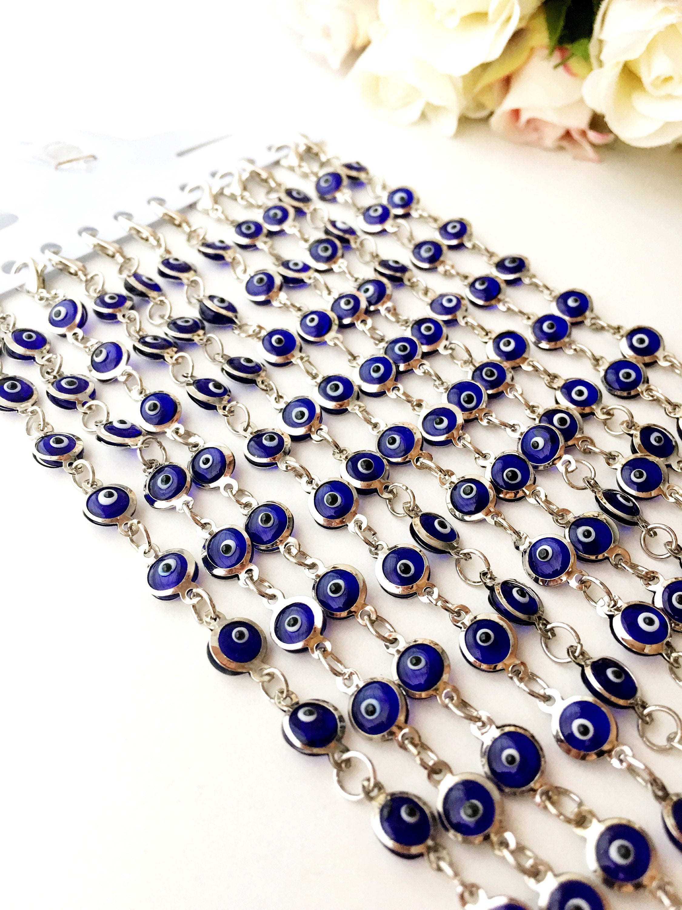 A beautiful silver chain bracelet featuring blue glass evil eye charms, showcasing handmade craftsmanship and elegant design.