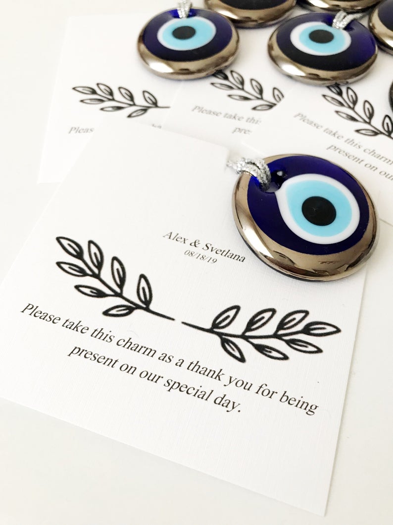 A collection of handmade silver evil eye beads with personalized cards, symbolizing good luck and protection, perfect for wedding favors.