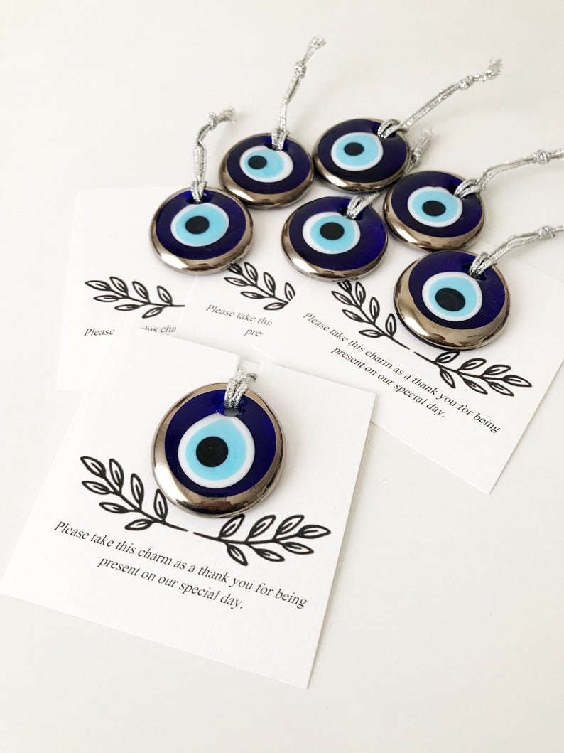 A collection of handmade silver evil eye beads with personalized cards, symbolizing good luck and protection, perfect for wedding favors.