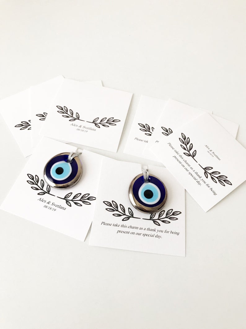 A collection of handmade silver evil eye beads with personalized cards, symbolizing good luck and protection, perfect for wedding favors.