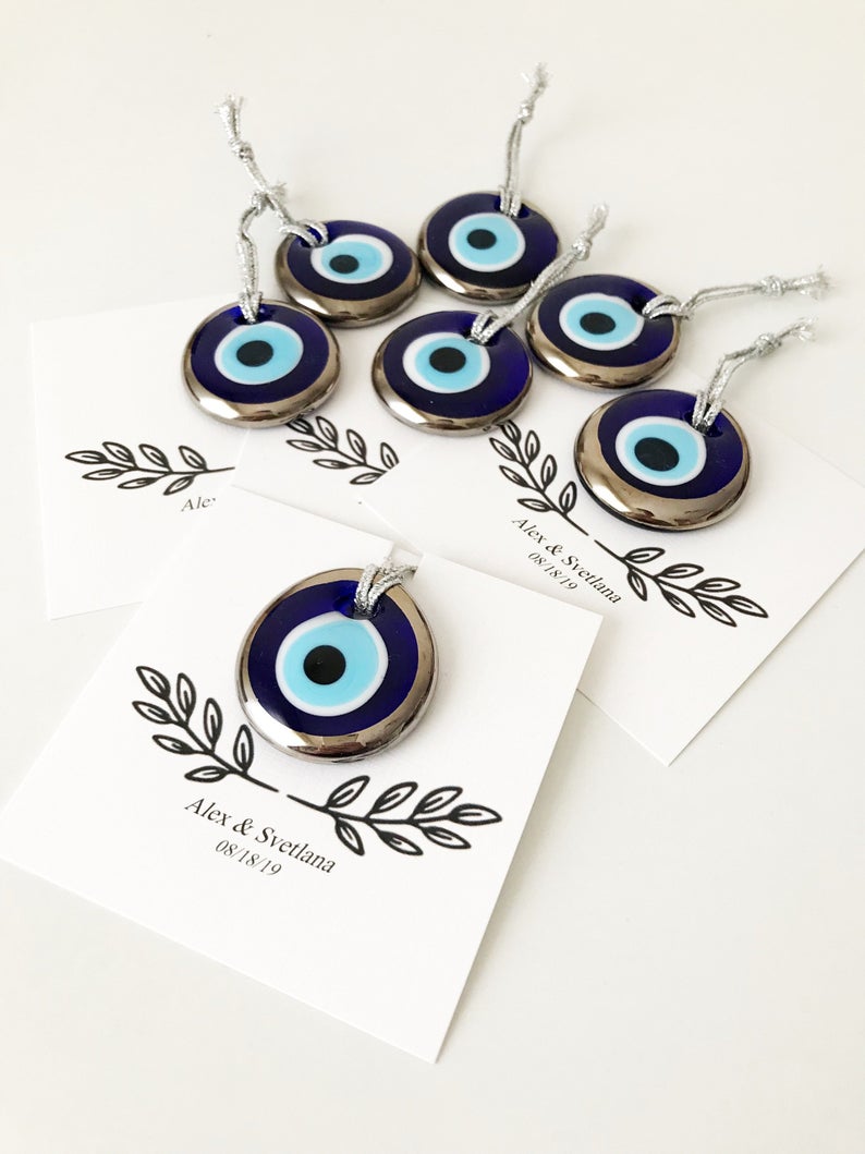 A collection of handmade silver evil eye beads with personalized cards, symbolizing good luck and protection, perfect for wedding favors.