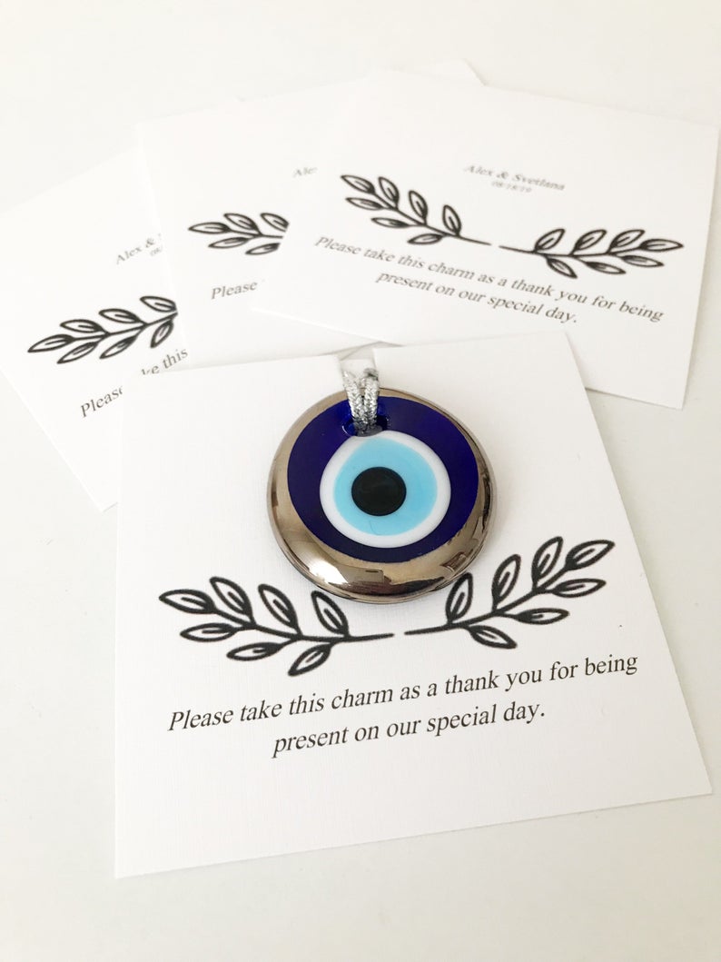A collection of handmade silver evil eye beads with personalized cards, symbolizing good luck and protection, perfect for wedding favors.