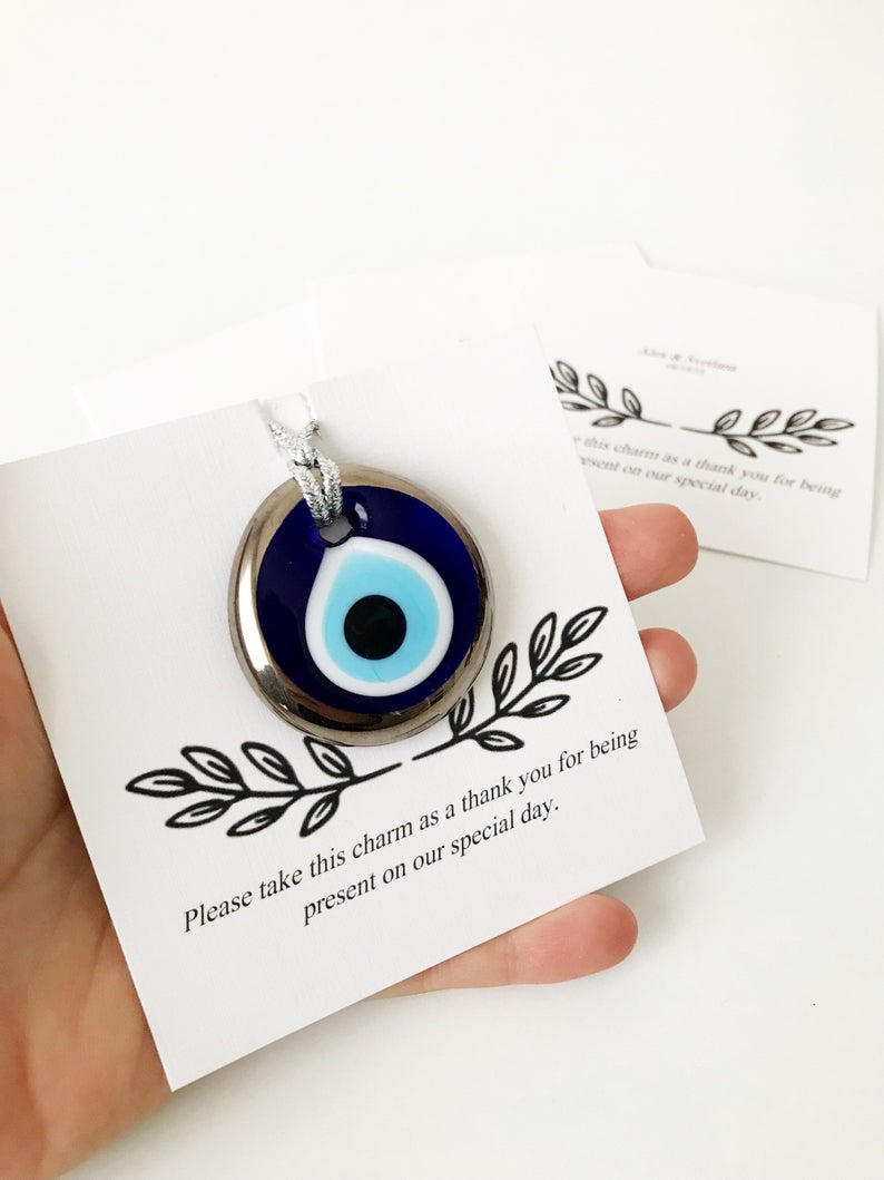 A collection of handmade silver evil eye beads with personalized cards, symbolizing good luck and protection, perfect for wedding favors.