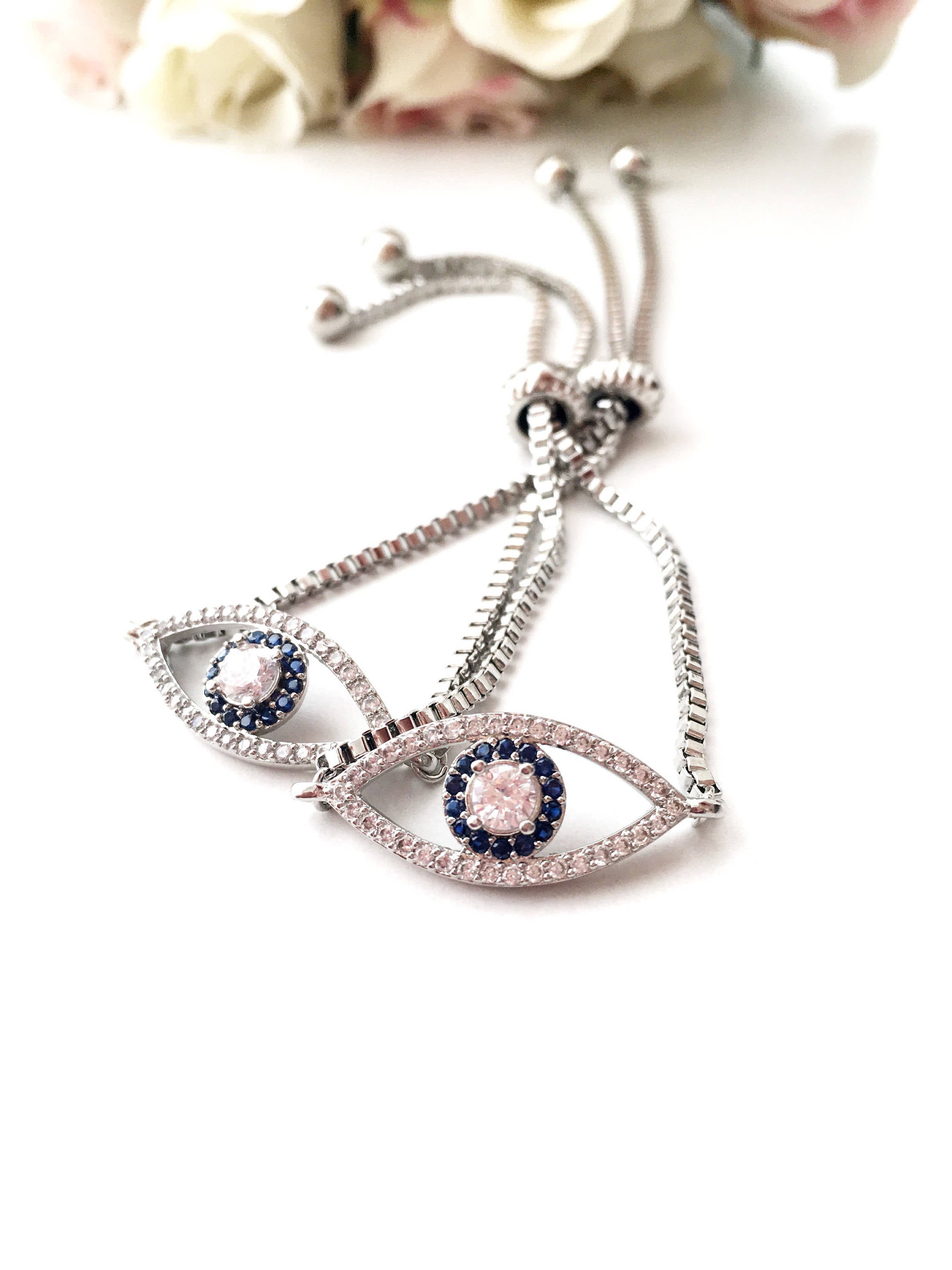 A beautiful set of handmade silver evil eye bracelets, featuring various designs including safety pin, baguette, and zirconia styles, all adjustable for comfort.