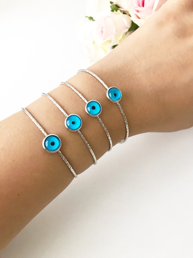 A delicate silver evil eye bracelet featuring a movable oval charm, crafted from tarnish-resistant stainless steel.