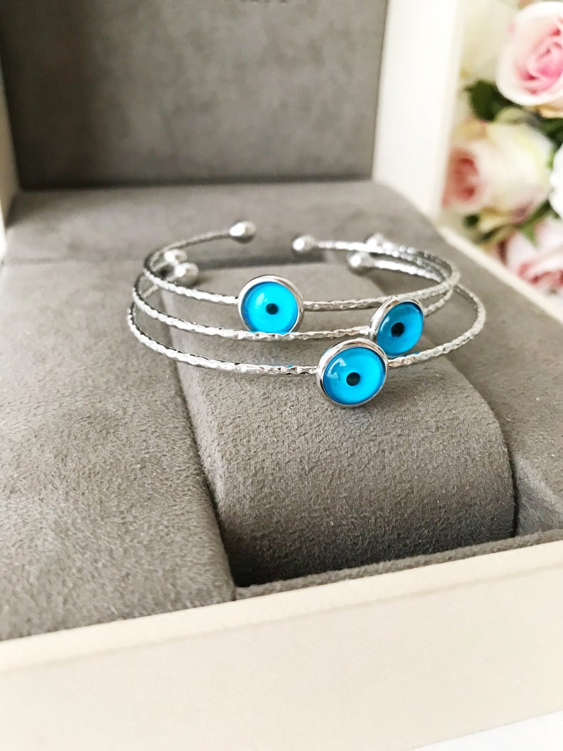 A delicate silver evil eye bracelet featuring a movable oval charm, crafted from tarnish-resistant stainless steel.